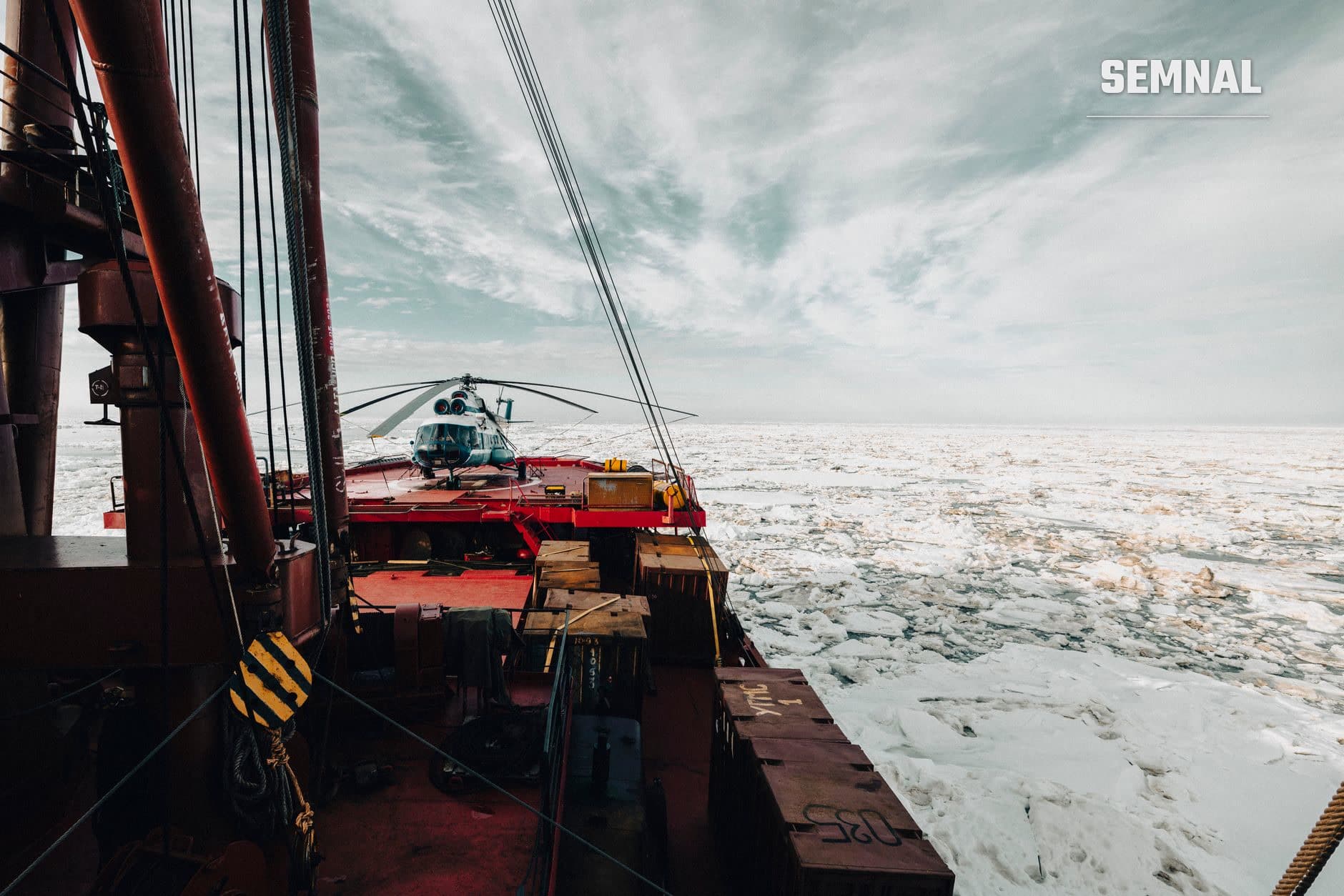 Puntea unui vas de cercetare polară cu elicopter pe platformă și gheață arctică fragmentată în fundal, ilustrând operațiuni de expediție științifică în regiunile polare extreme. (Foto: Dmitriy Ryndin / Pexels)