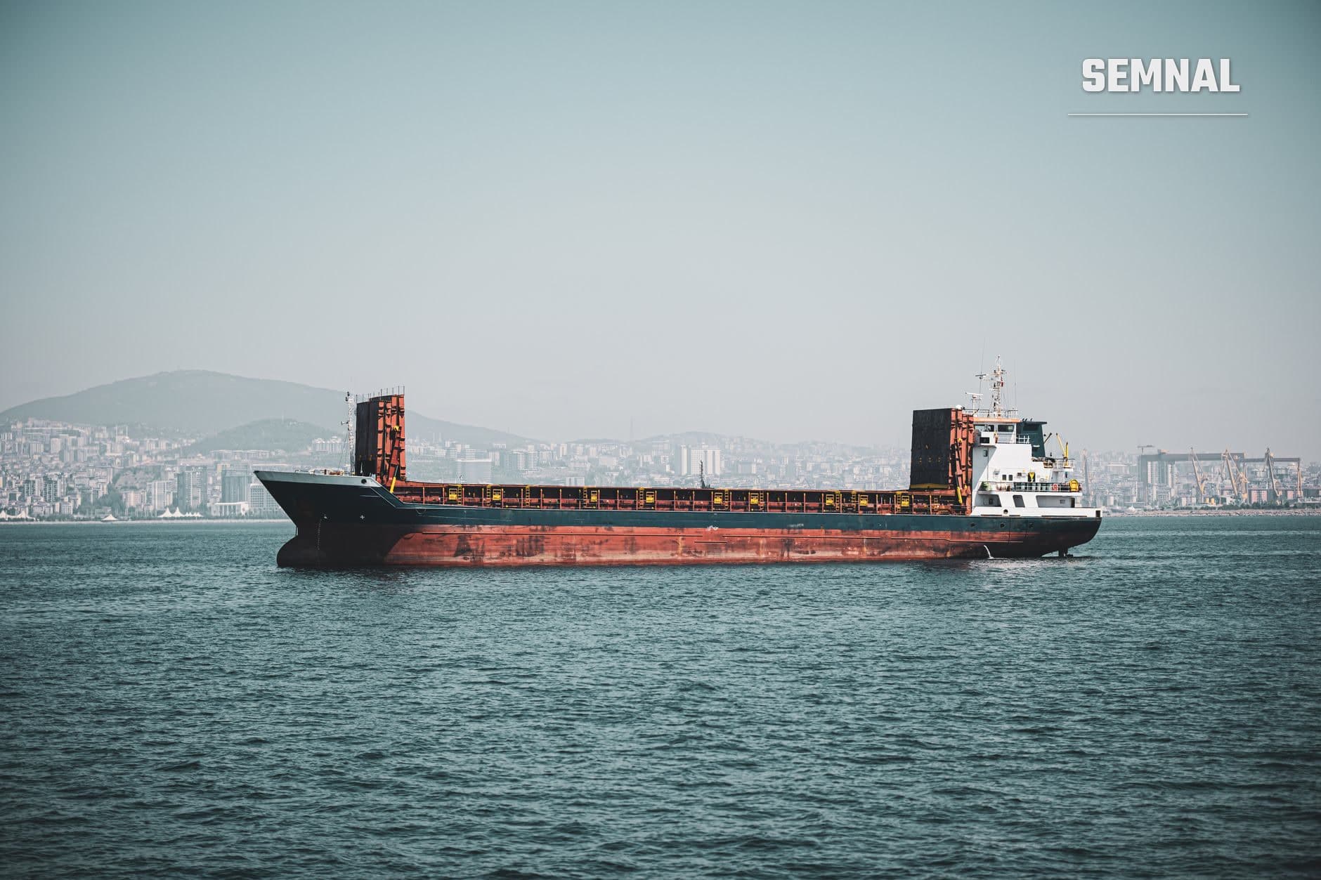 Navă de marfă cu containers în Marea Neagră, în fața unui port urban, ilustrând transporturile comerciale și securitatea coridorului de cereale. (Foto: Şahin Doğdu / Pexels)