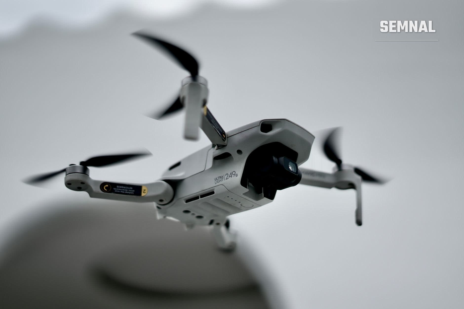 Dronă albă cu patru elice în zbor pe cer gri, cu cameră video frontală și detalii negre, reprezentând tehnologia care a blocat temporar aeroportul din Luxemburg. (Foto: Adika Budiman / Pexels)