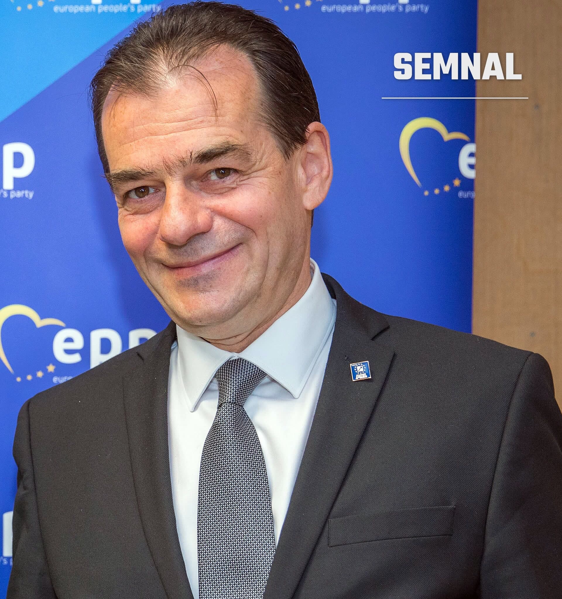 Ludovic Orban, în costum negru și cravată gri, fotografiat la un eveniment cu fundal albastru. (Foto: European People's Party)