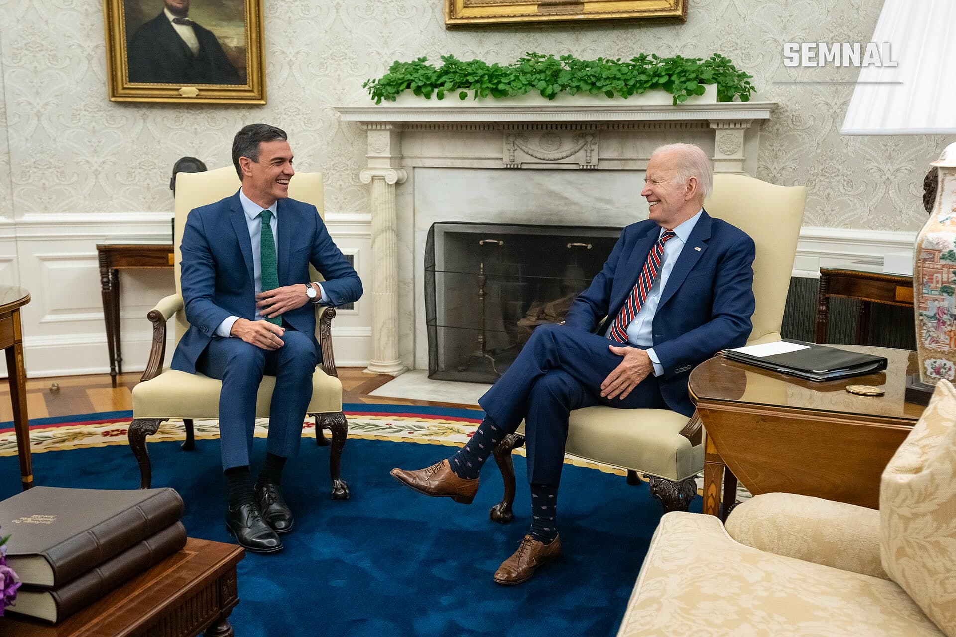 Pedro Sanchez, premierul Spaniei, în costum albastru și cravată verde, sedând într-un fotoliu crem în Biroul Oval, purtând o conversație cu o altă personalitate politică în costum oficial. (Foto: Office of the President of the United States)