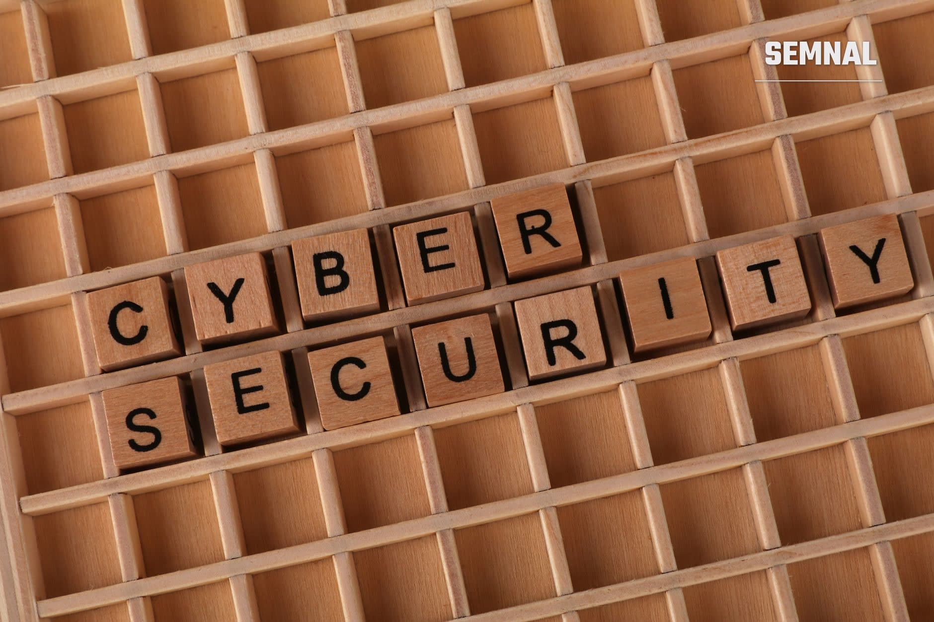 Cuburi de lemn cu litere formând cuvintele 'CYBER SECURITY' aranjate într-o cutie de sortare din lemn, simbolizând protecția datelor și securitatea cibernetică. (Foto: Ann H / Pexels)