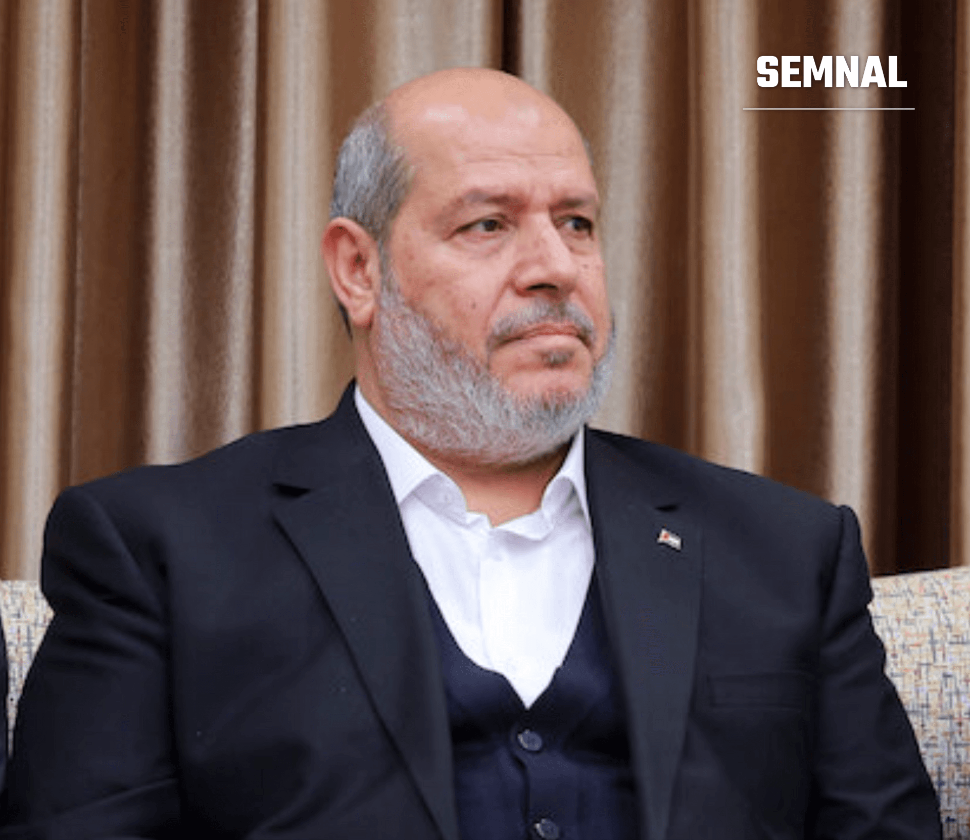 Khalil al-Hayya, lider Hamas, portret în plan apropiat, îmbrăcat formal cu costum negru și cămașă albă, ședință într-un interior elegant cu draperii, expresie serioasă. (Foto: Khamenei.ir)