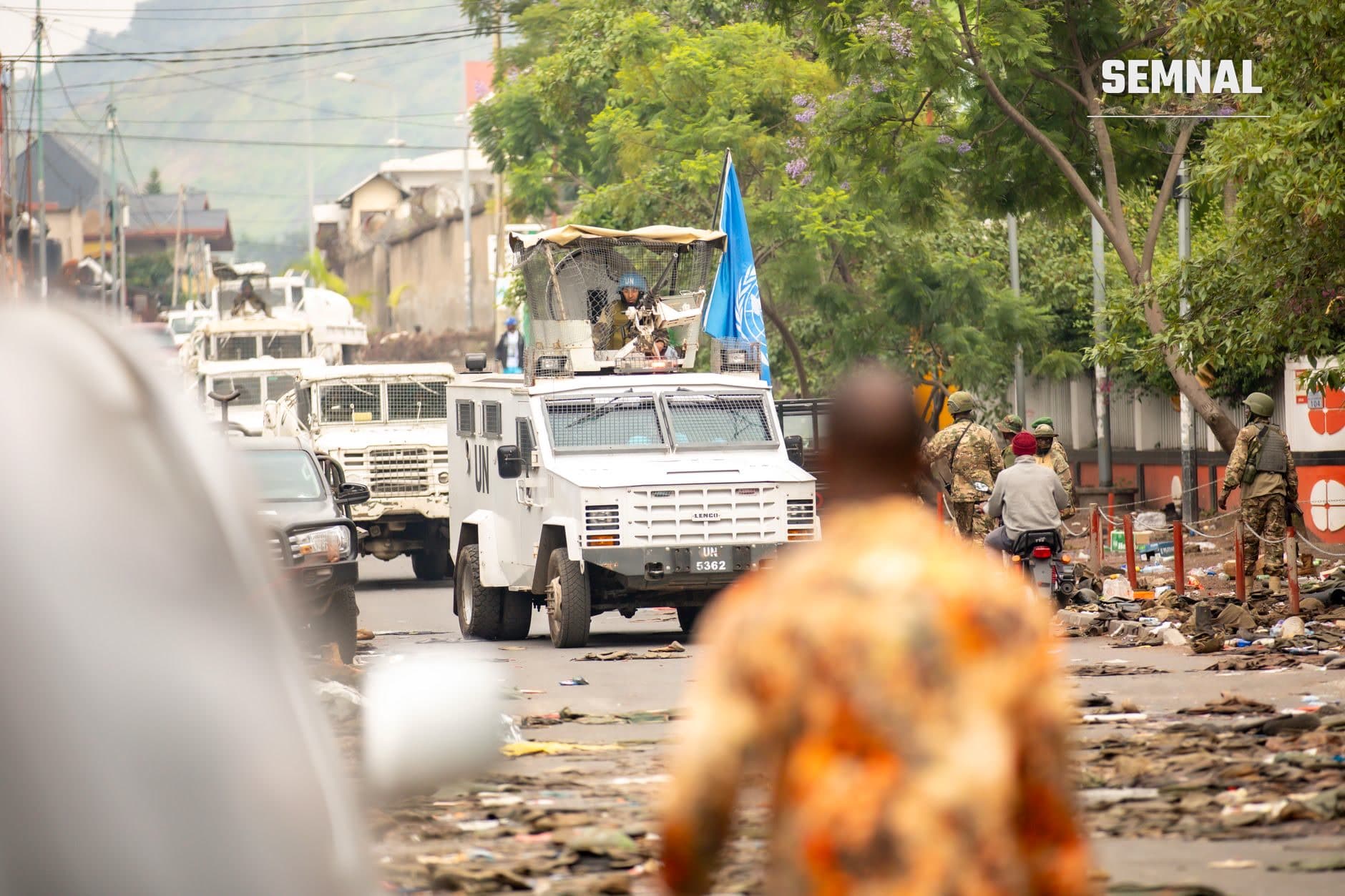 Vehicul militar blindat ONU și soldați în operațiune pe o stradă prafuită, midst dărâmături, sugerând operații de retapă militară în zonă de conflict. (Foto: Safi Erneste / Pexels)