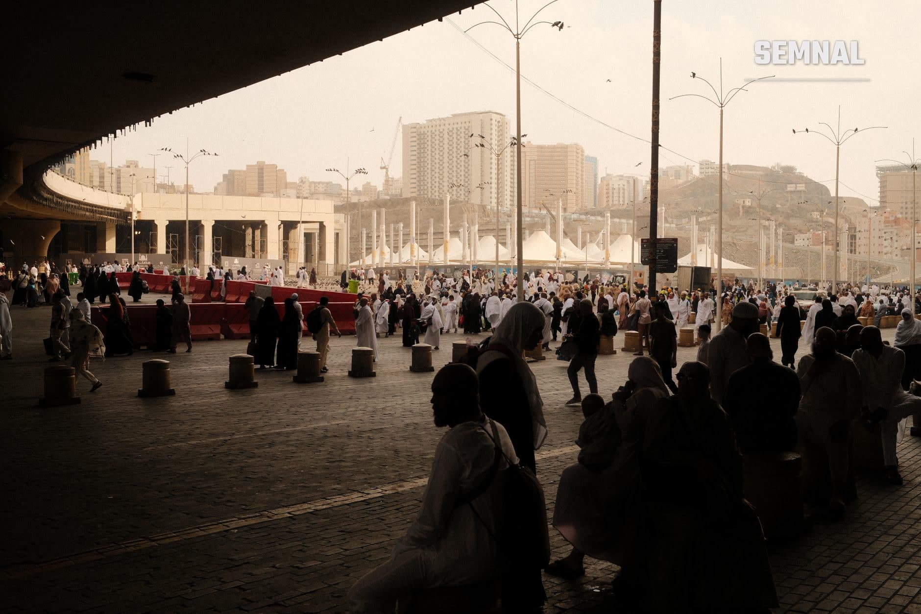 Mulțime de pelerini în piața Masjid al-Haram din Mecca, cu peretele viaductului și orizontul orasului saudit în fundal, ilustrând locul sacru care face subiectul paciului regional. (Foto: Jasurbek Ruzmat / Pexels)