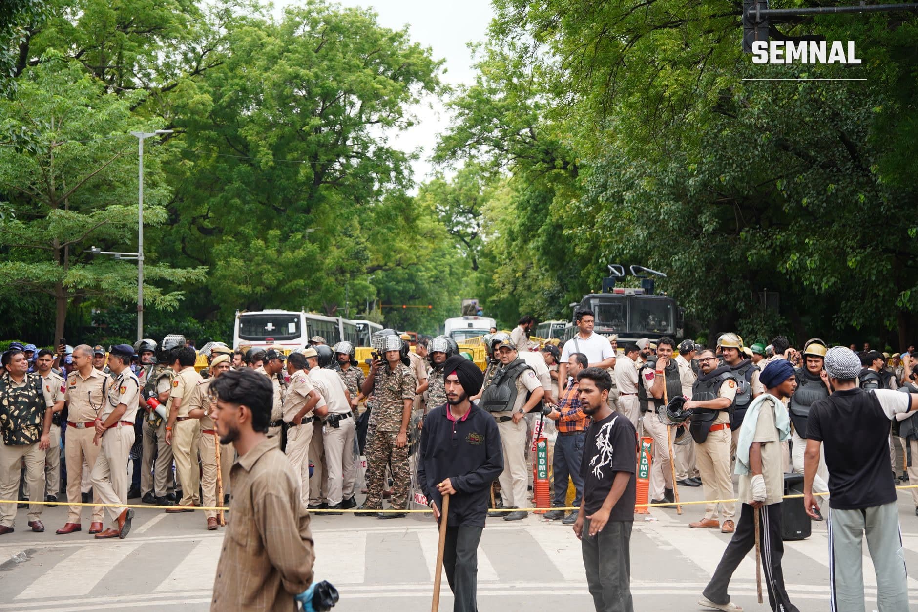 Mulțime de polițiști și militari în stradă la Delhi, cu civili și vehicule de securitate, în timp ce se derulează o operațiune de reținere în masă în contextul protestelor. (Foto: Harikrishan Jakhar / Pexels)