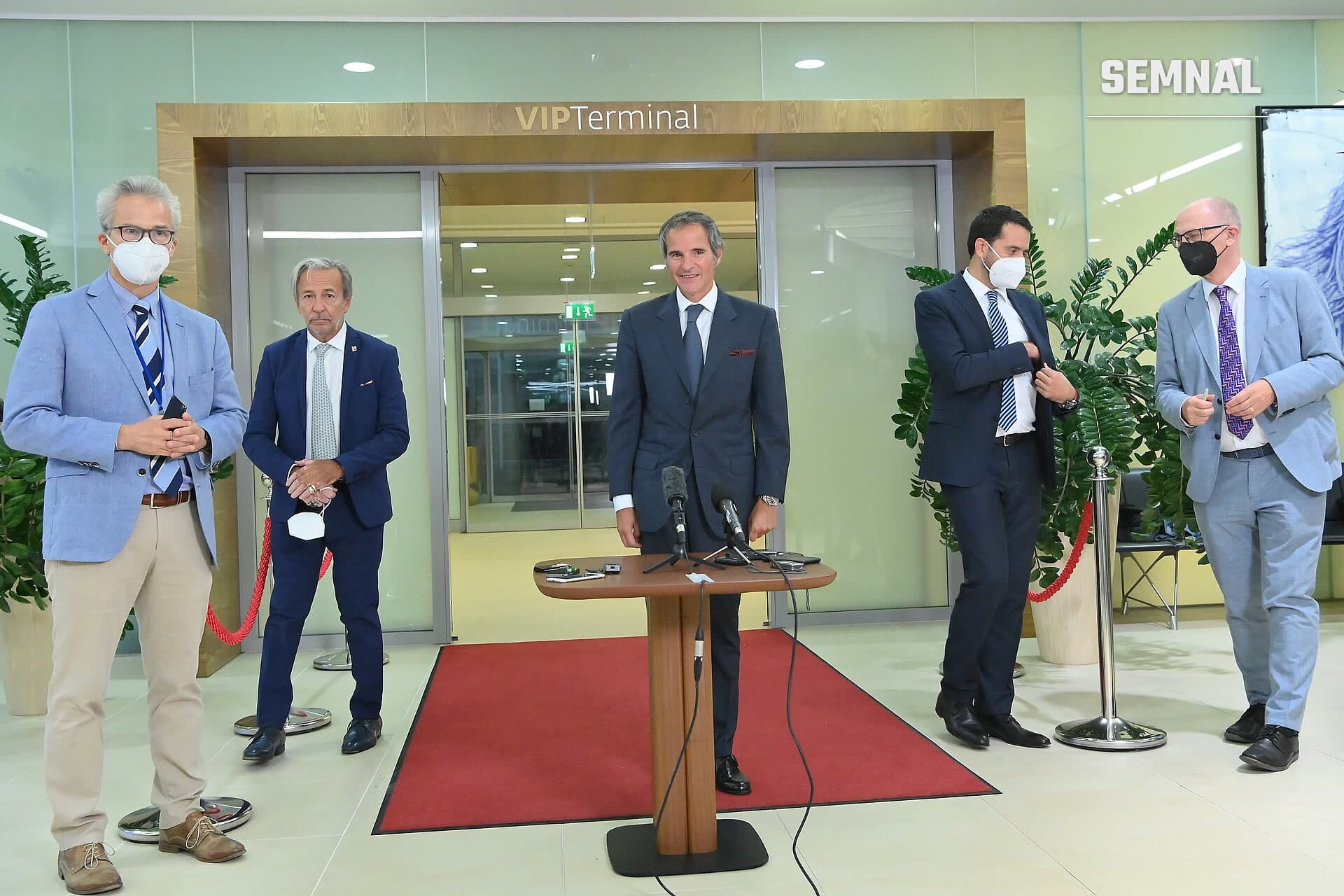 Mohammad Eslami, șeful Organizației pentru Energie Atomică a Iranului, la pupitru cu microfoane în VIP Terminal, purtând costum negru și cravată roșie. (Foto: IAEA Imagebank)