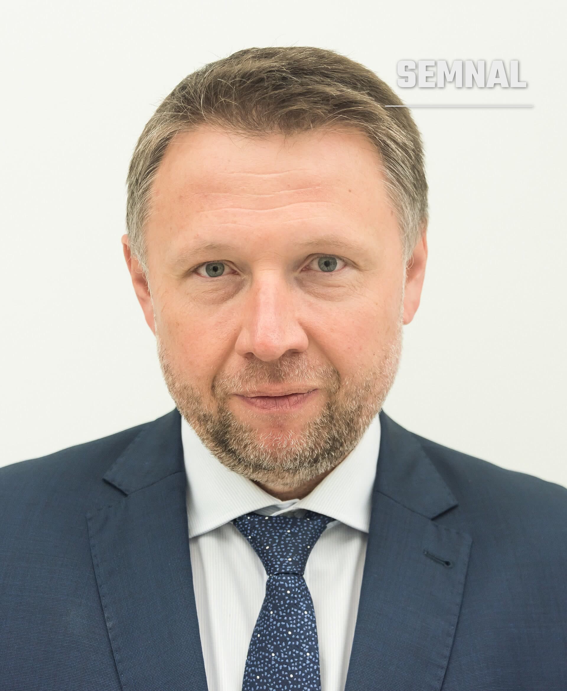 Marcin Kierwiński, portret în costum bleumarin, cămașă albă și cravată albastră cu model, pe fundal alb. (Foto: Adrian Grycuk)