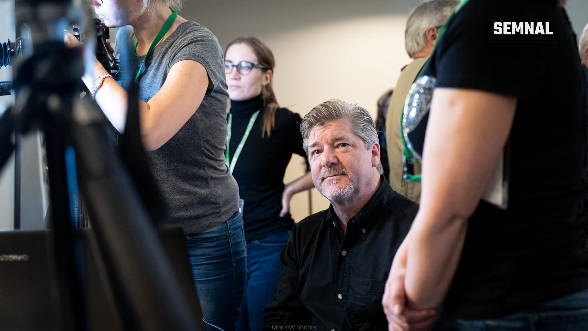 Peter Krogh, privind spre cameră, înconjurat de participanți cu ecusoane verzi și de echipament de filmare într-un spațiu interior. (Foto: MorroW Shoots)