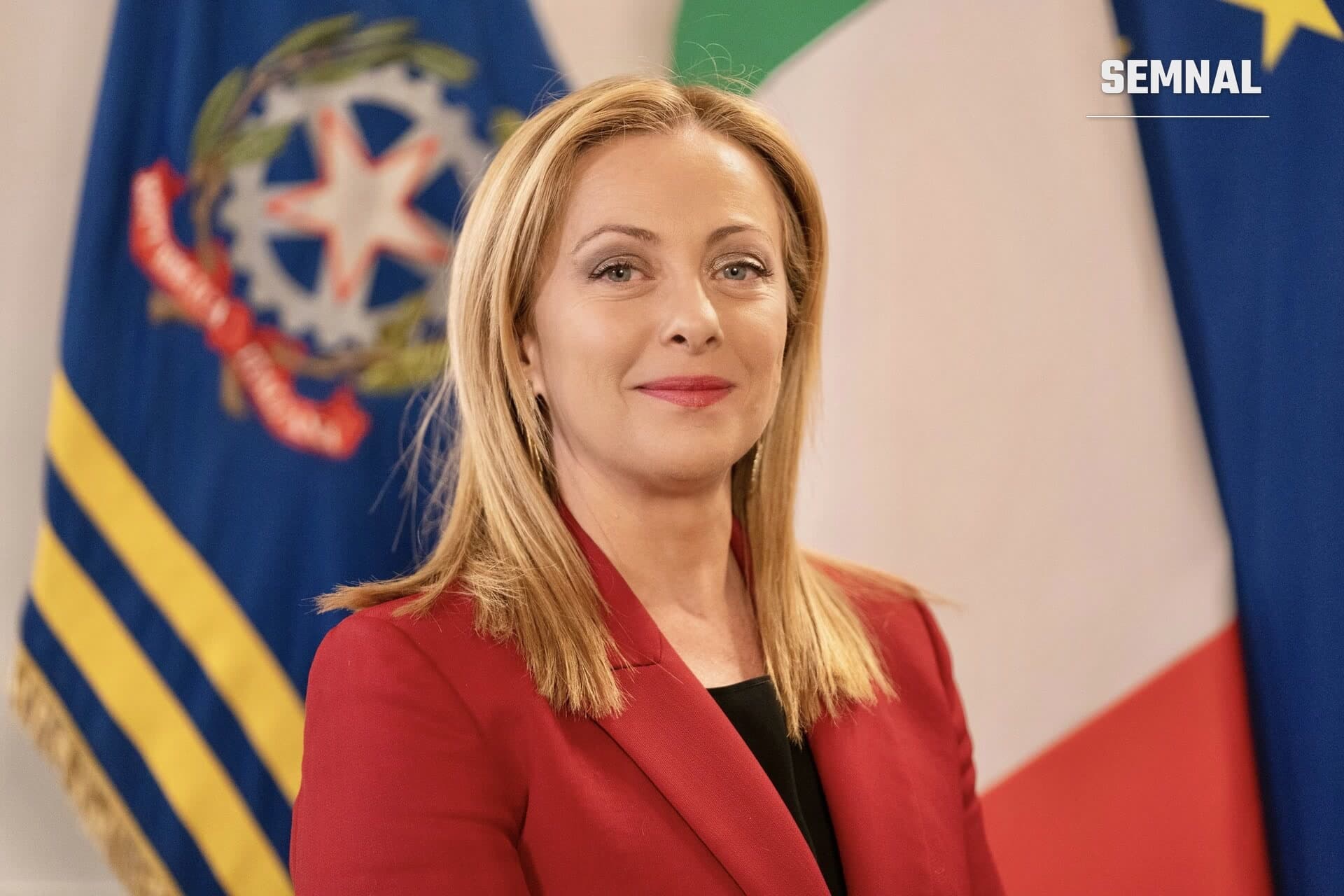 Giorgia Meloni, în sacou roșu, în fața drapelelor Italiei și Uniunii Europene (Foto: Governo italiano)