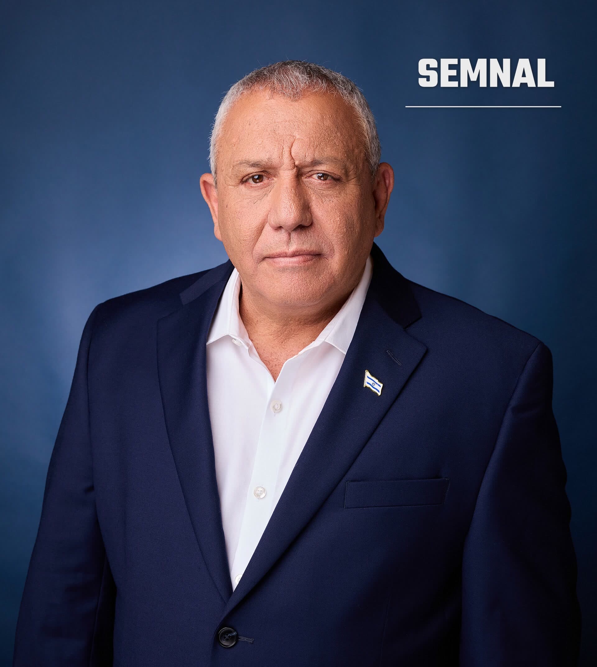 Gadi Eisenkot, în costum bleumarin și cămașă albă, cu o insignă cu steagul Israelului pe rever, pe fundal albastru. (Foto: יהב טרודלר (Yahav Trudler - Yahav Studio))