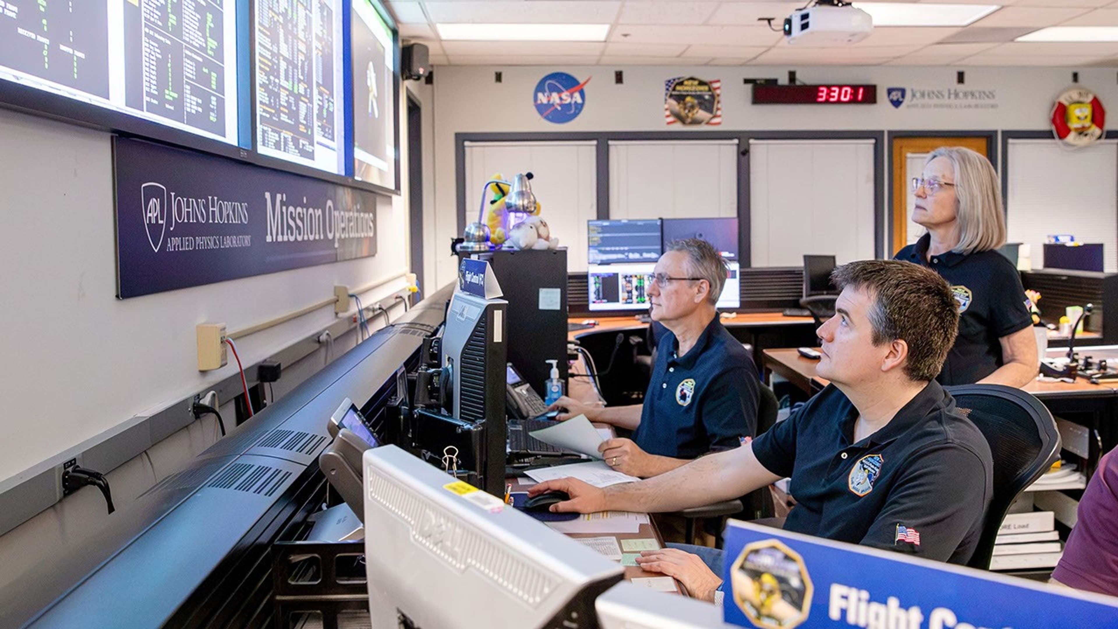 Controlori de zbor monitorizează telemetria sondei New Horizons pe ecrane, la centrul de operațiuni al Laboratorului de Fizică Aplicată Johns Hopkins