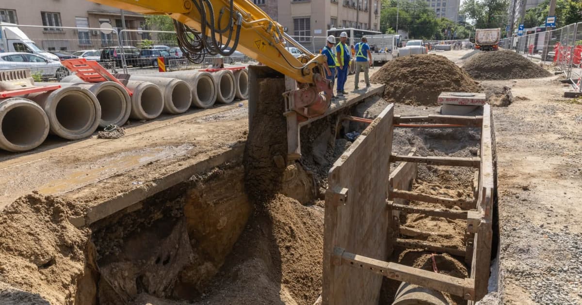 Lucrări de modernizare a liniei de tramvai și a rețelei de canalizare pe o bulevard din București, cu utilaje și șanțuri săpate lângă șine