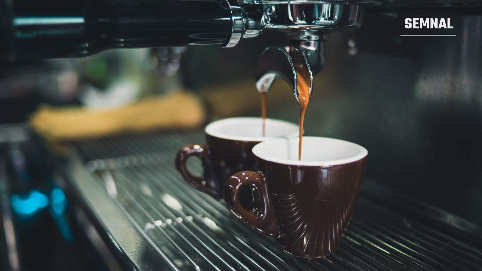 Cafea fierbinte turnată dintr-un espressor profesional, cu abur ridicându-se din ceașcă