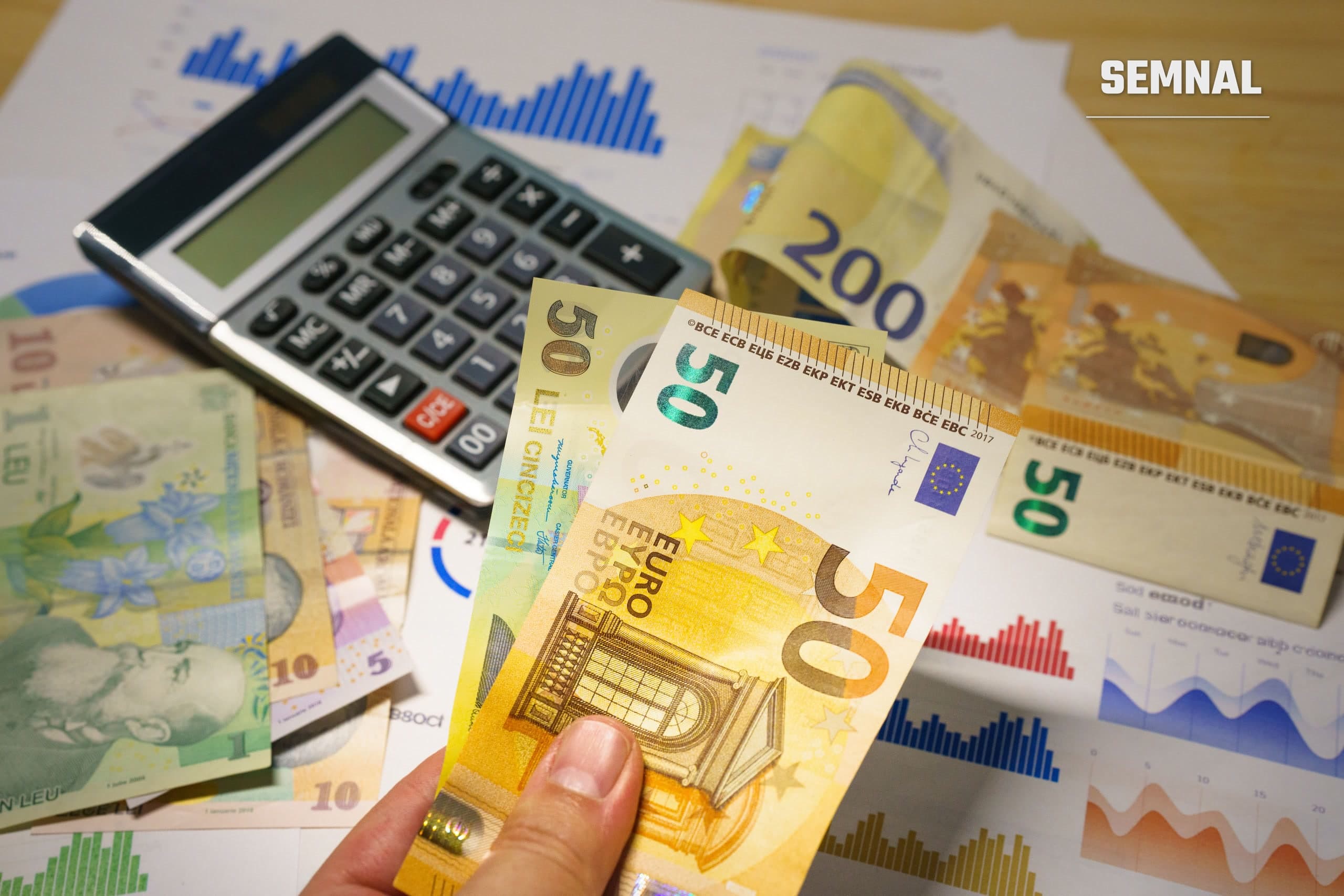 Bancnote de euro și lei românești așezate lângă un calculator, ilustrând o verificare fiscală în sectorul schimbului valutar