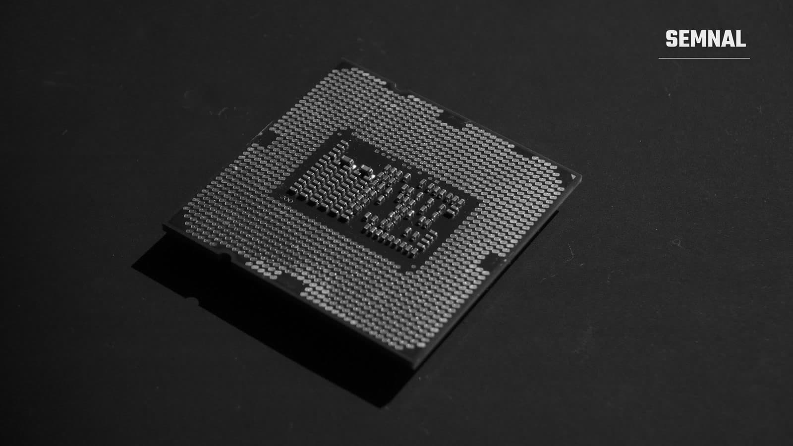 Procesor de computer fotografiat în prim-plan, cu pinii metalici vizibili pe partea inferioară a cipului