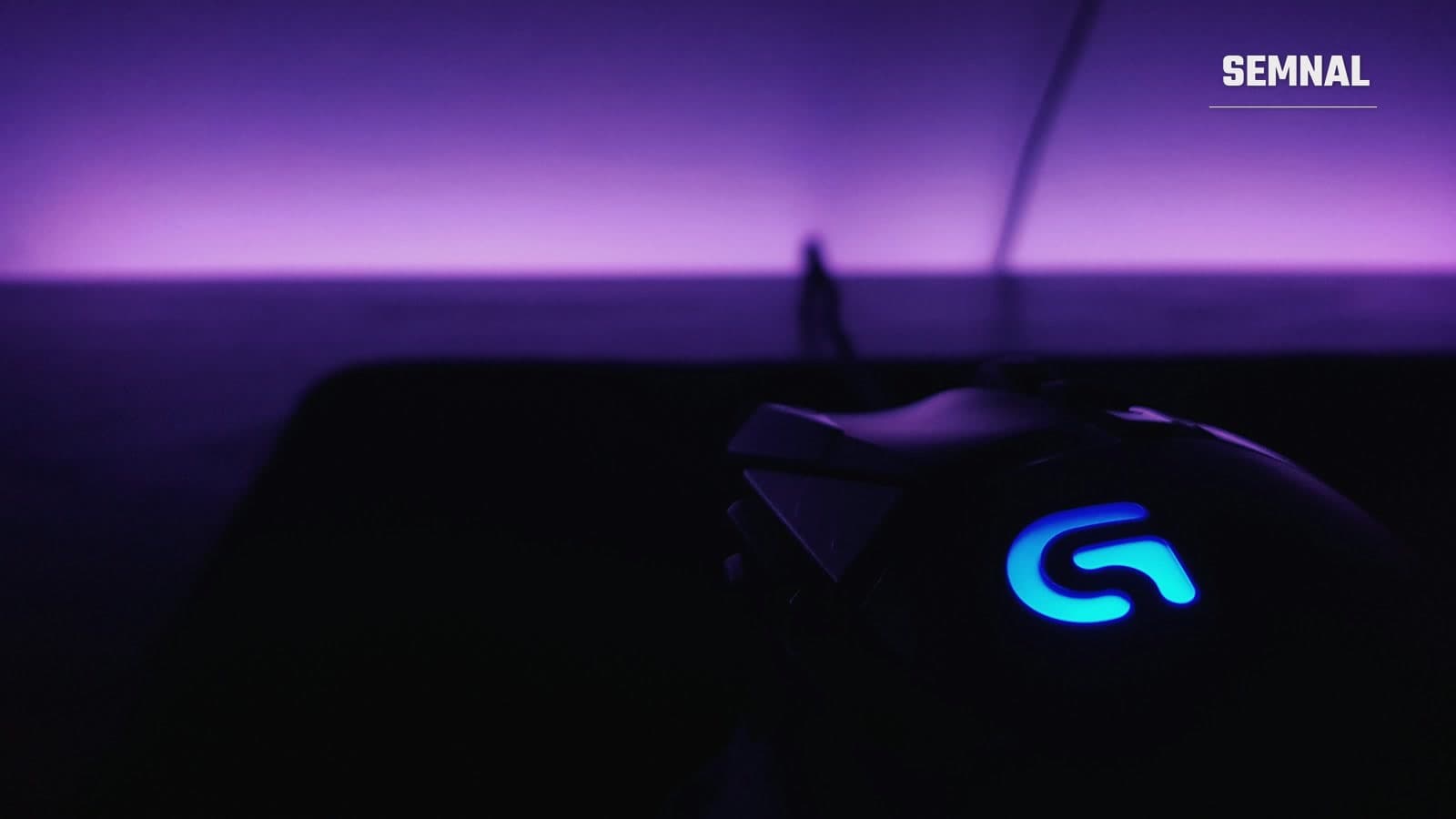Mouse de gaming Logitech negru cu accente albastre, fotografiat pe un birou lângă o tastatură