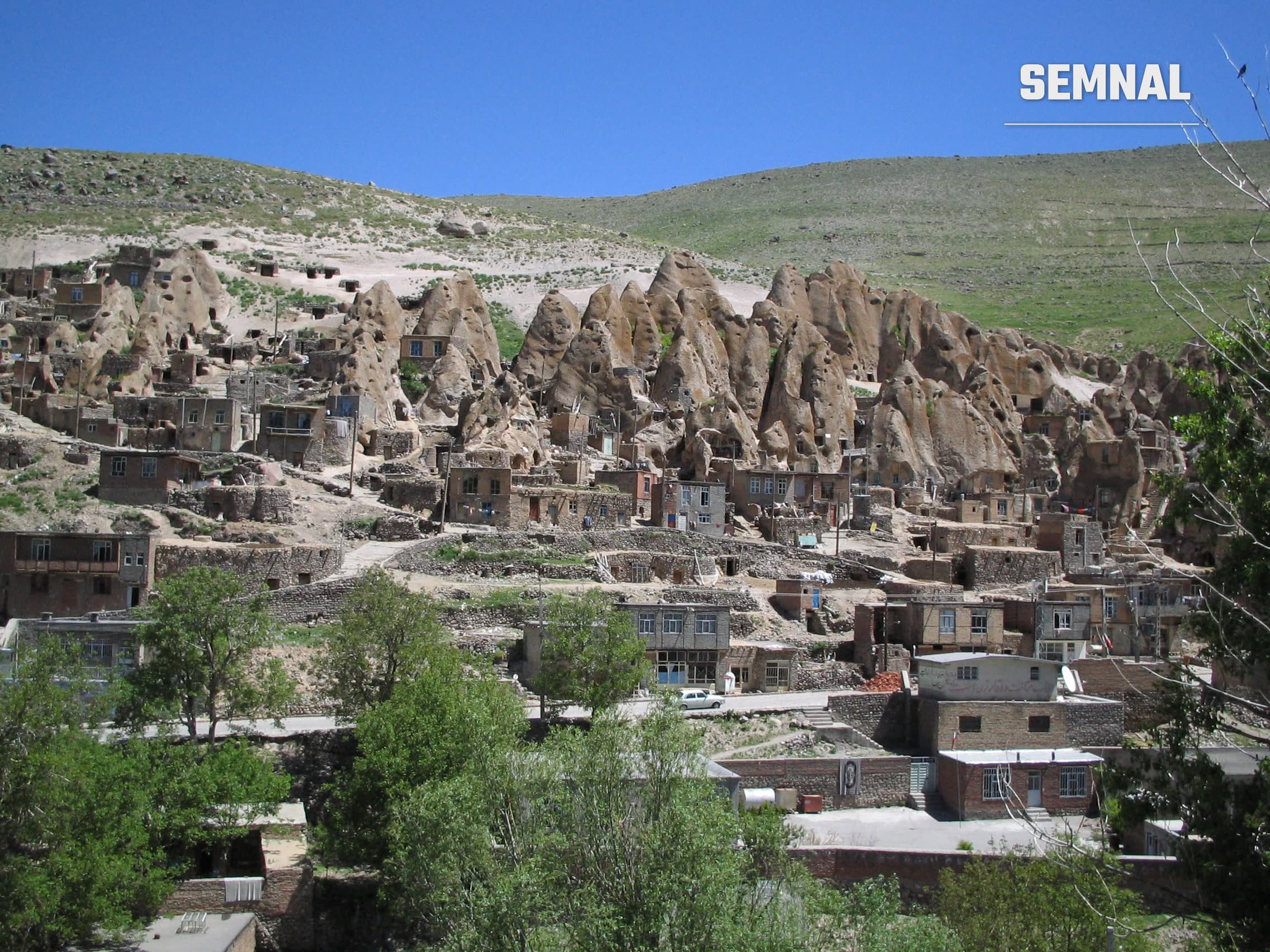 Case sculptate în conuri de rocă vulcanică în satul Kandovan, Iran, cu ferestre și uși tăiate direct în stâncă