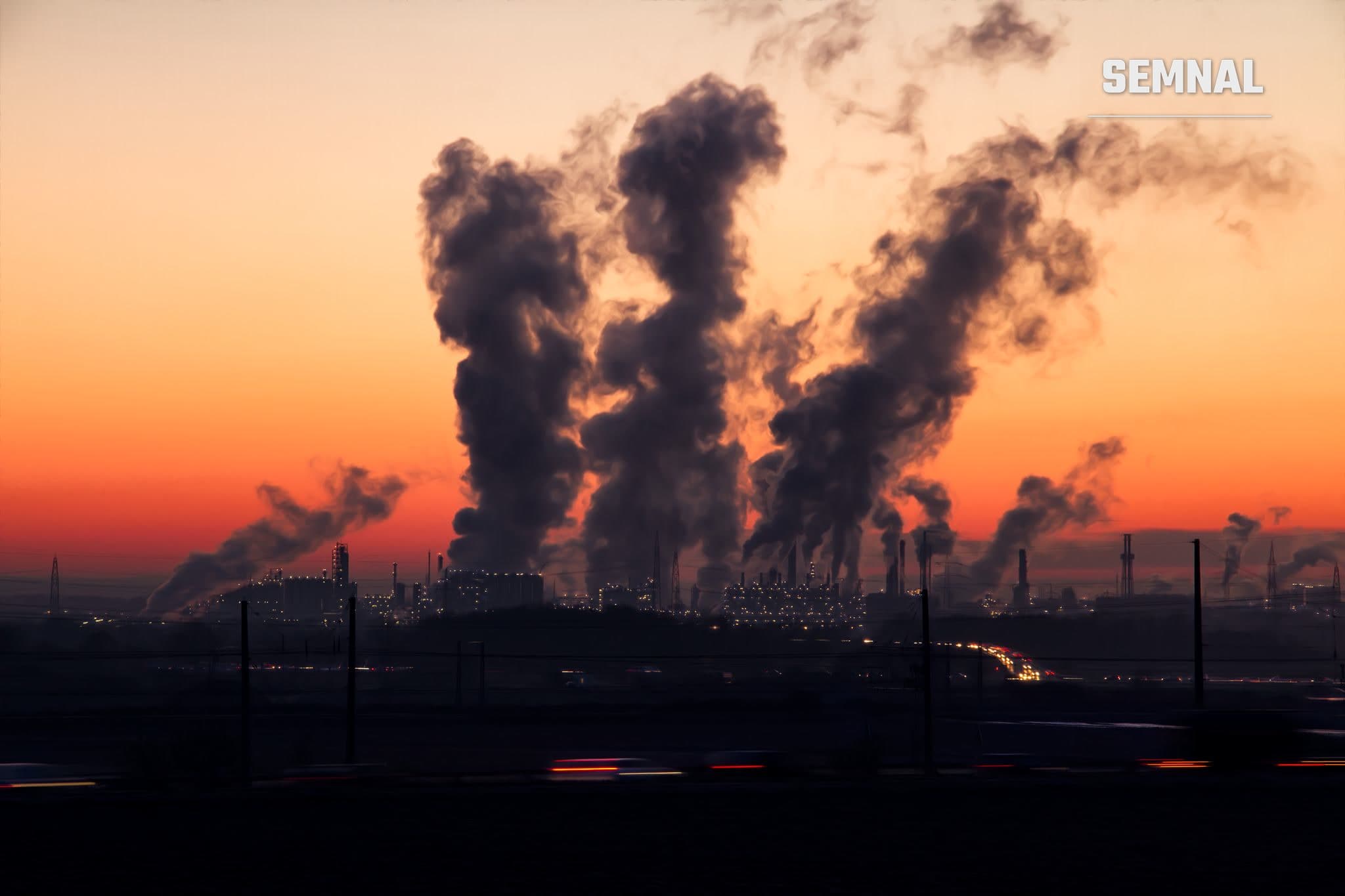 Fum industrial pe fondul unui cer înroșit de apus, simbol al poluării aerului
