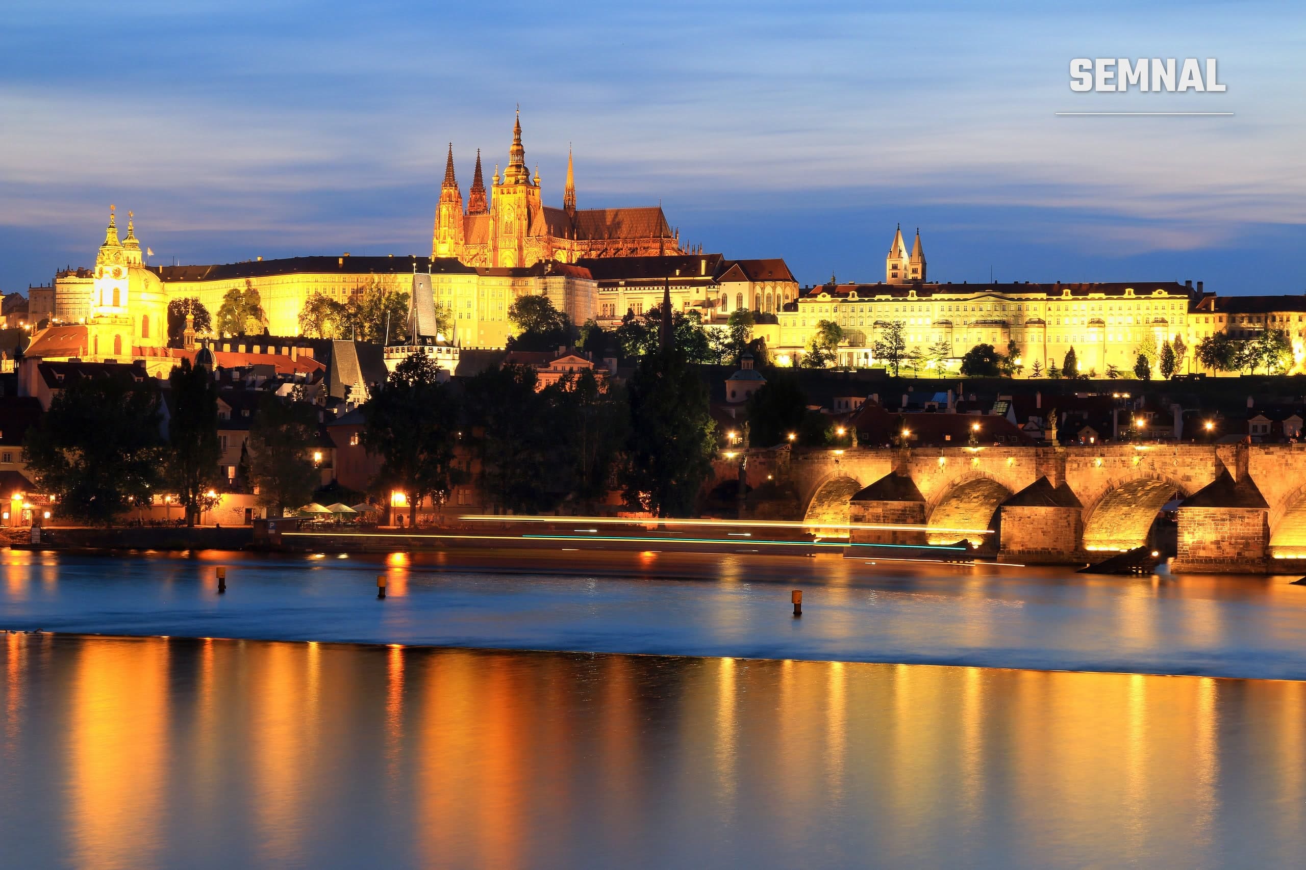 Castelul Praga și Podul Carol, luminate noaptea, reflectate în râul Vltava. Imagine ilustrativă
