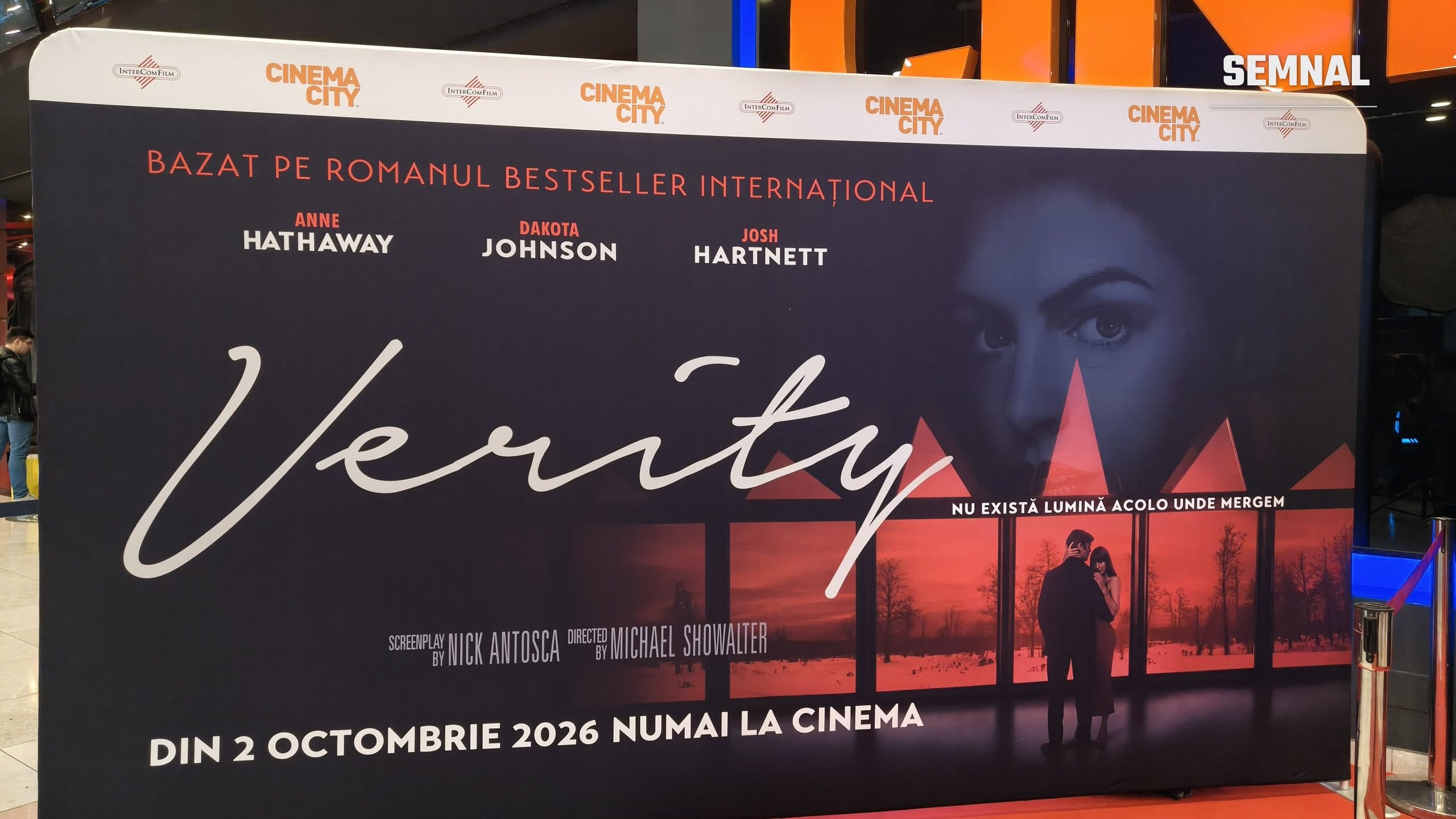 Panou promoțional al filmului Verity, cu Anne Hathaway, Dakota Johnson și Josh Hartnett, la intrarea unui cinematograf Cinema City