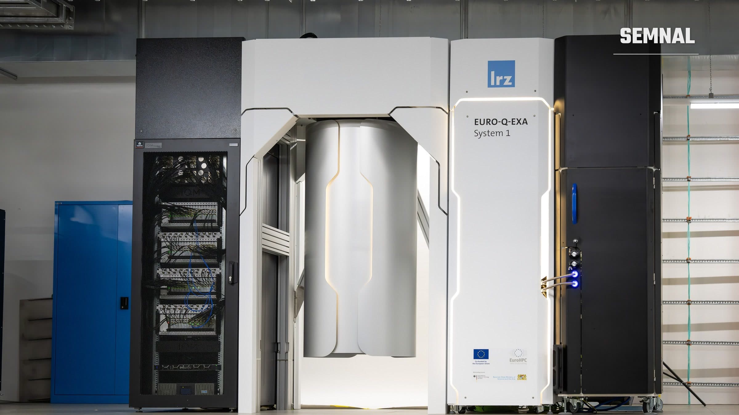 Calculatorul cuantic Euro-Q-Exa din hala Centrului de Supercomputing Leibniz: o carcasă albă cu criostat central, flancată de rafturi de control negre