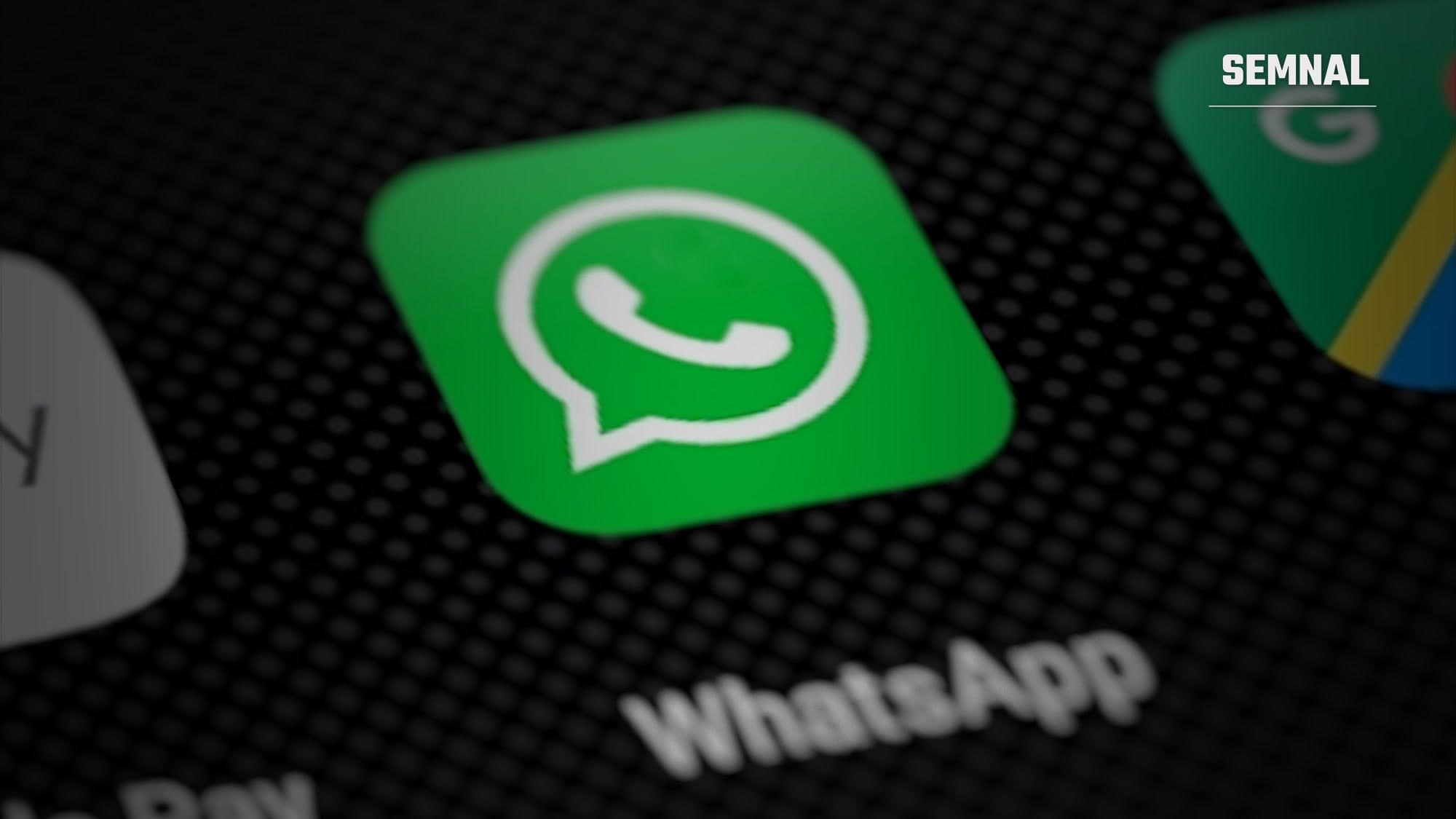 Pictograma aplicației WhatsApp pe ecranul unui smartphone, văzută în prim-plan, pe un fundal întunecat cu alte aplicații