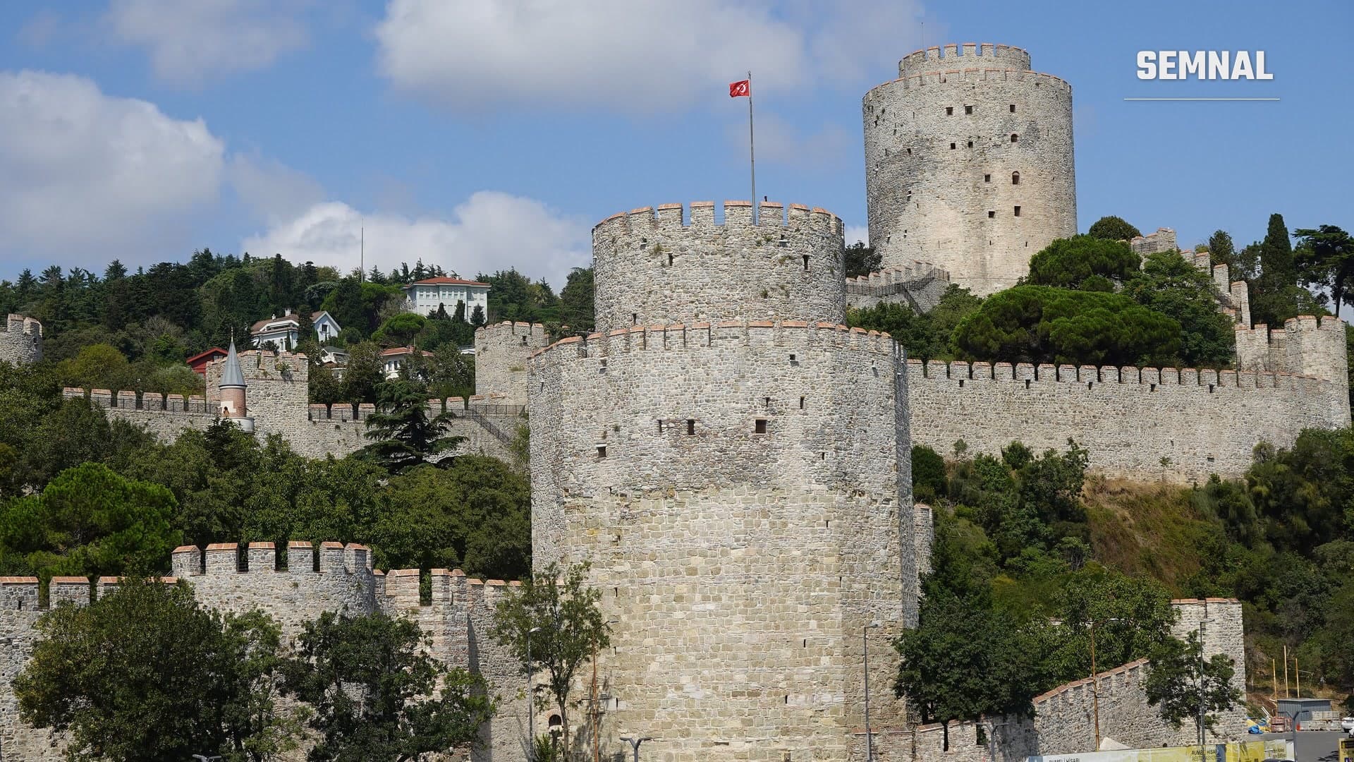 Turnurile rotunde de piatră și zidurile cu creneluri ale fortăreței Rumeli Hisarı, cu steagul Turciei, pe malul Bosforului, la Istanbul