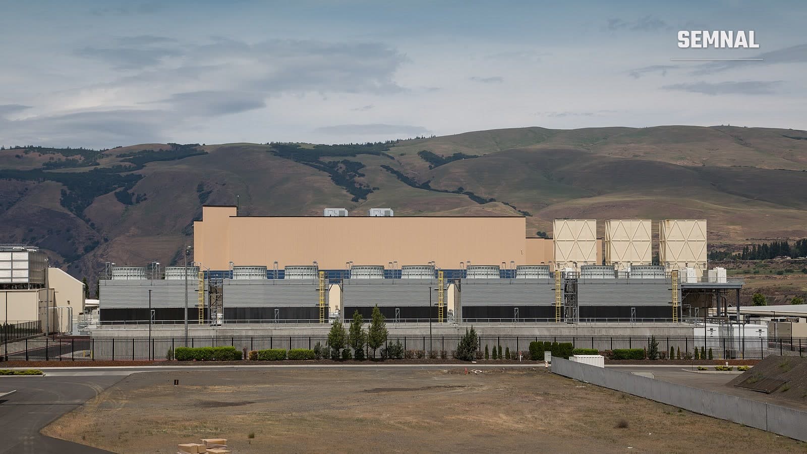 Clădirea centrului de date Google din The Dalles, Oregon, cu turnuri de răcire în fața unor dealuri