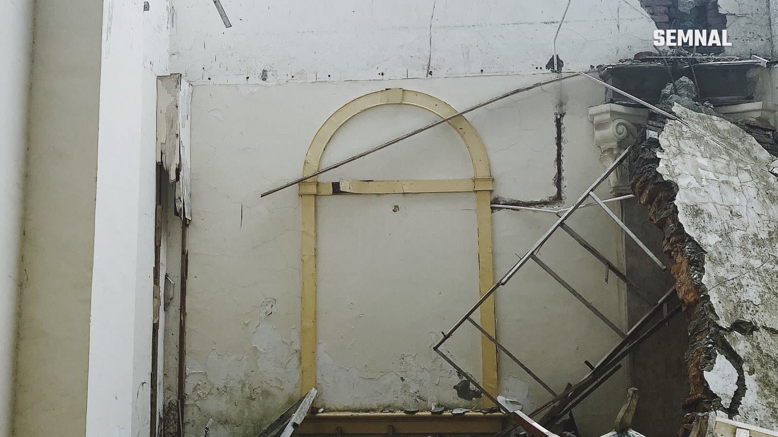 Interior al unei clădiri parțial demolate, cu moloz și ziduri avariate, imagine ilustrativă pentru distrugerile provocate de atacurile aeriene
