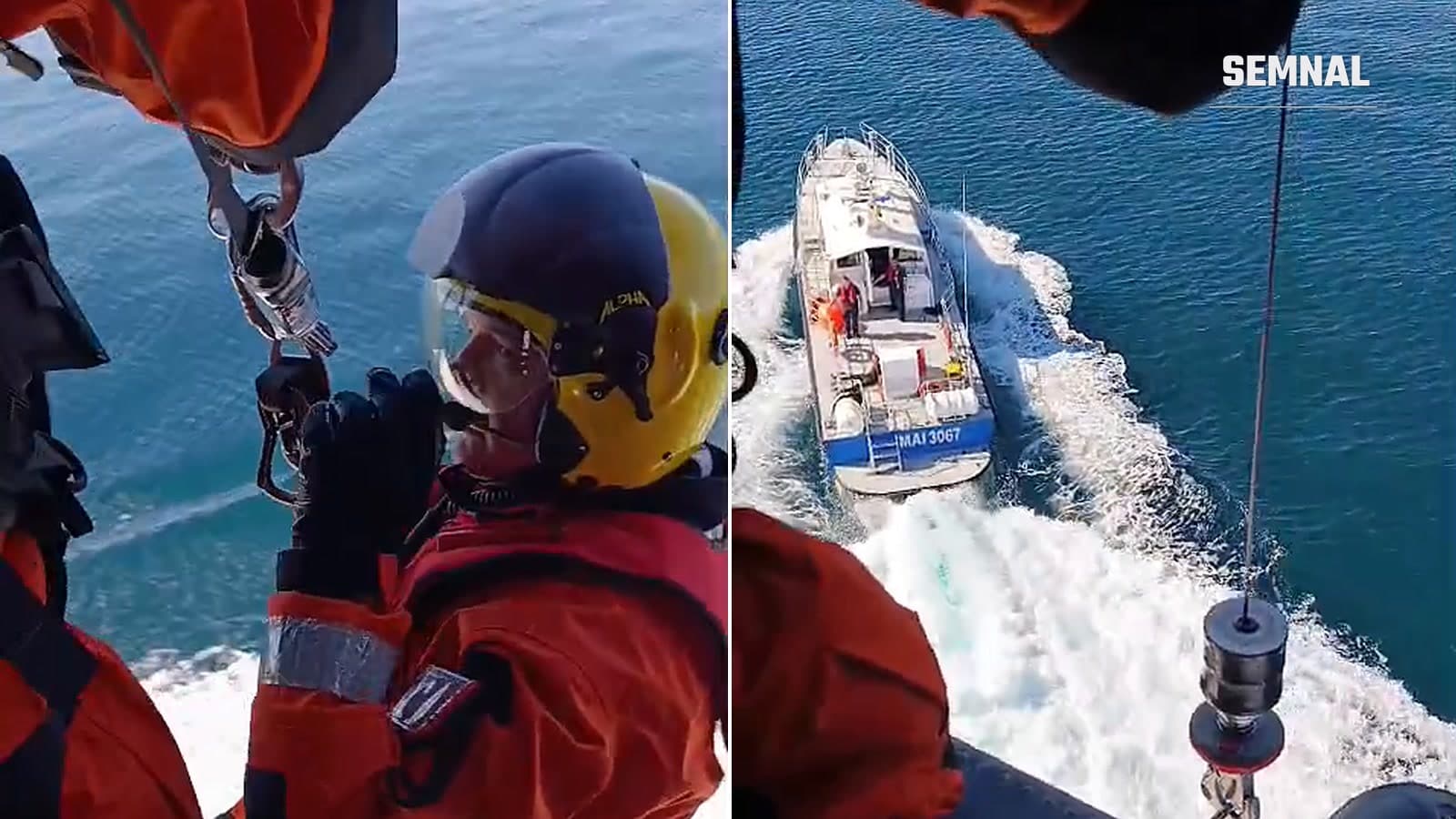 Salvator MAI suspendat de troliul elicopterului deasupra mării și navă a Gărzii de Coastă care navighează sub elicopter