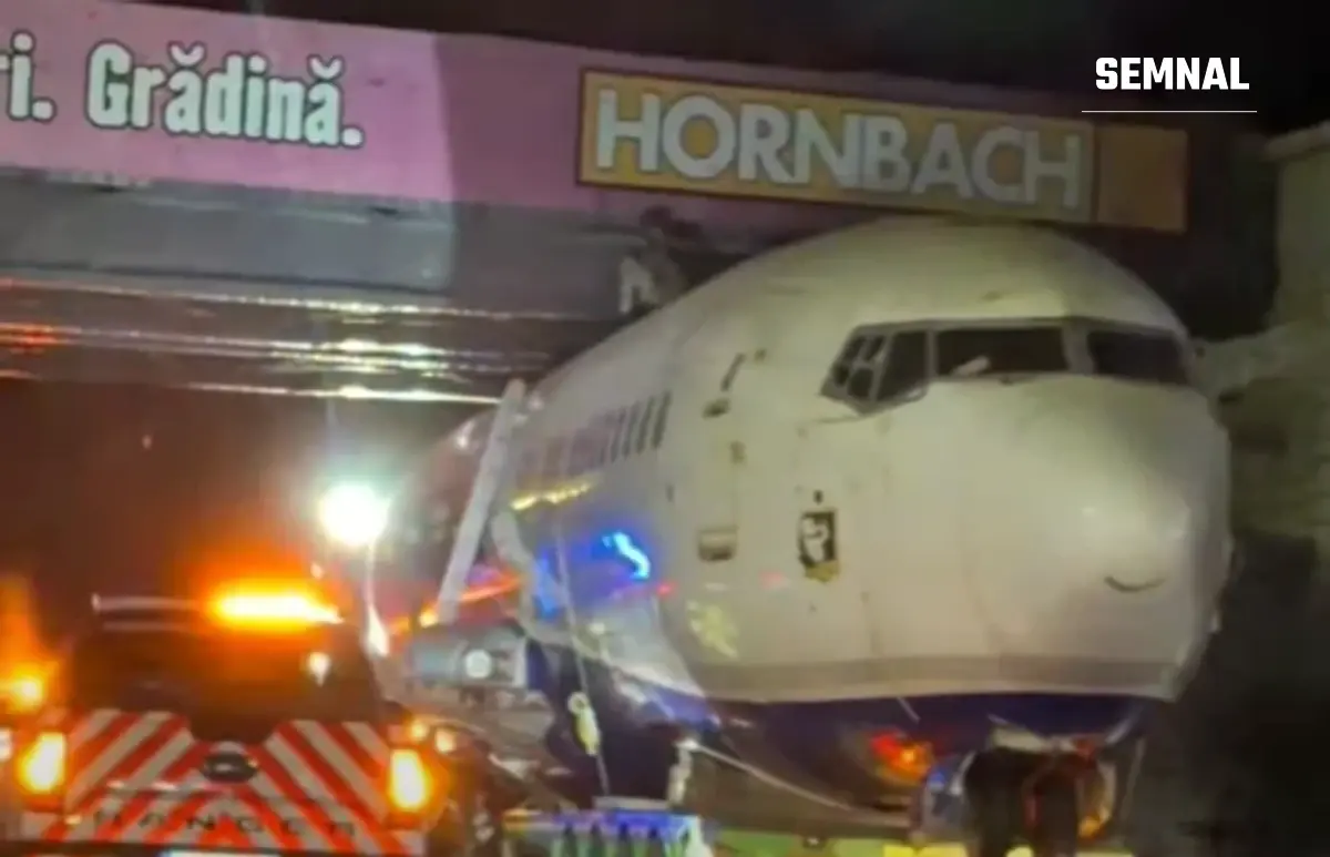 Botul unui avion de pasageri transportat pe un trailer, noaptea, blocat lângă structura unui magazin Hornbach, cu lumini de girofar vizibile