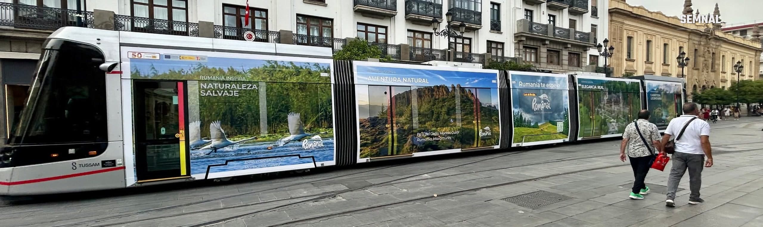Tramvaiul TUSSAM din Sevilla, colantat cu imagini din România: Delta Dunării, Creasta Cocoșului din Maramureș și un castel, sub sloganul „Rumanía inspira”