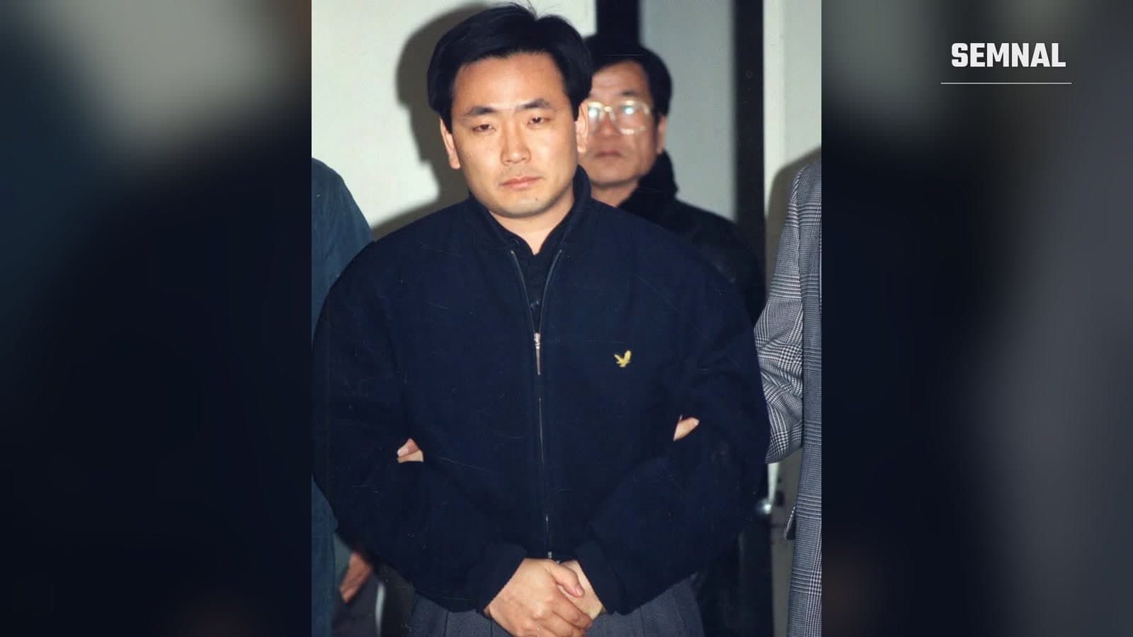 Kim Dong-sik, agent nord-coreean capturat în 1995, într-o geacă bleumarin, escortat de anchetatori sud-coreeni