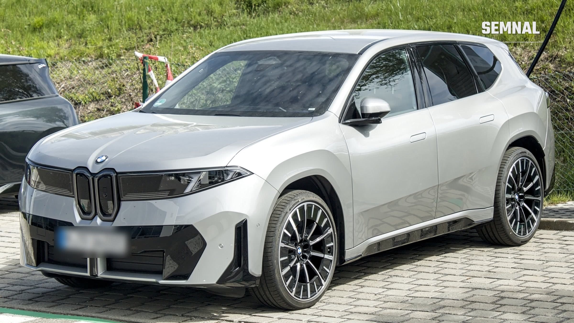 SUV-ul electric BMW iX3 din generația Neue Klasse, în culoare gri deschis, parcat pe o alee pavată, văzut din față și din lateral