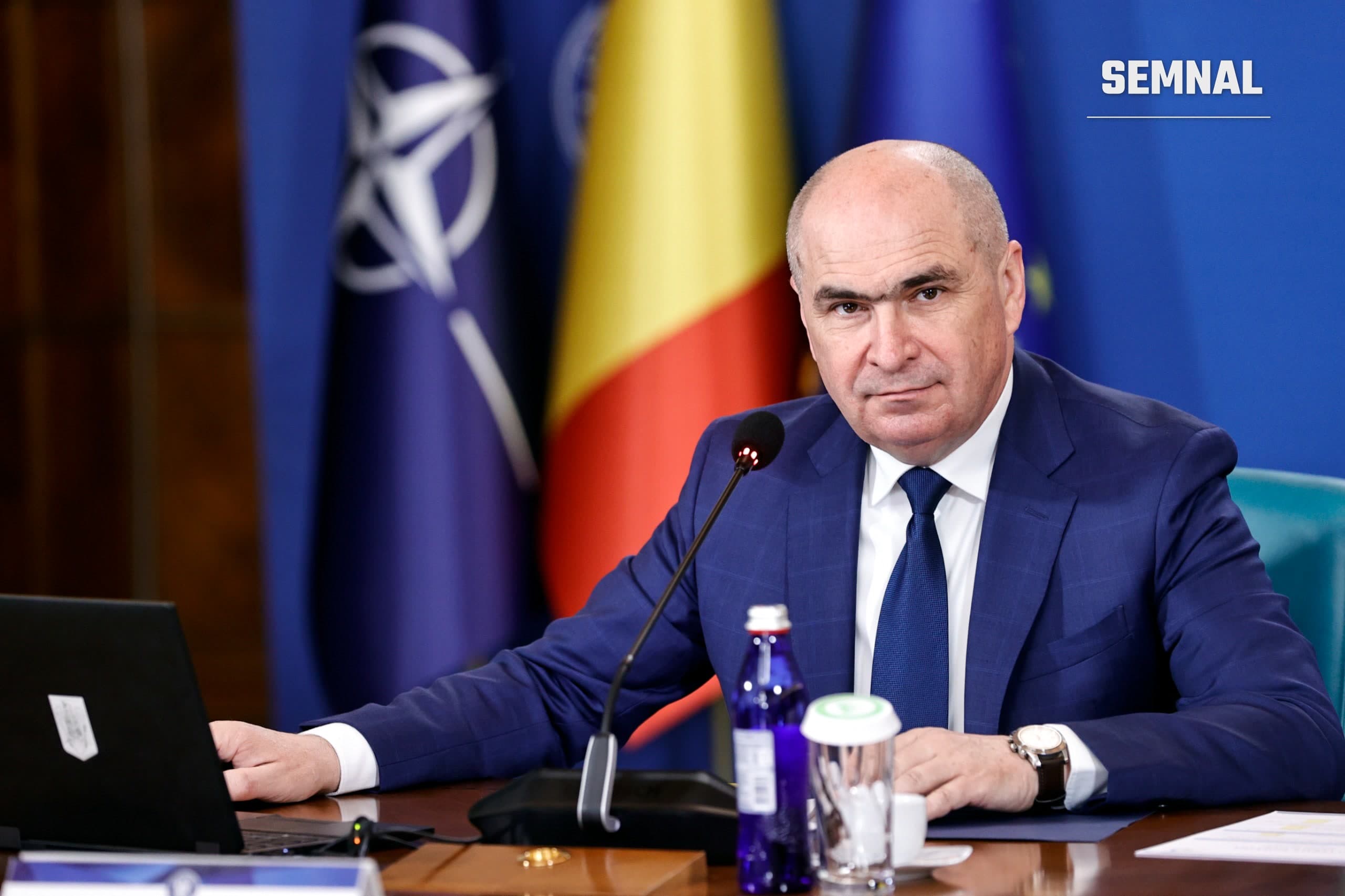 Ilie Bolojan la masa ședinței de Guvern, în fața drapelelor României, NATO și UE, aprilie 2026. Foto: gov.ro (Guvernul României)