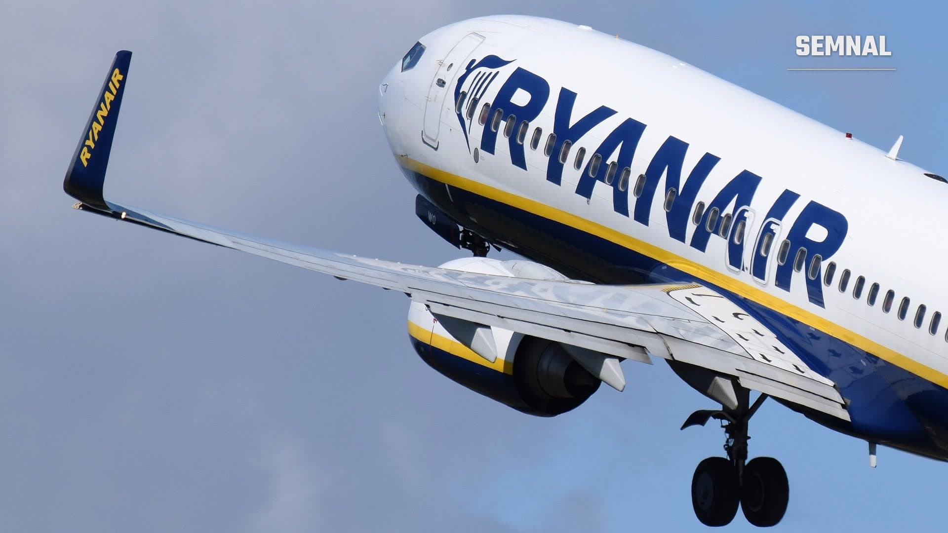 Boeing 737-800 al companiei Ryanair în momentul decolării, cu sigla albastră pe fuselaj și pe aripioara de la capătul aripii, pe un cer cu nori