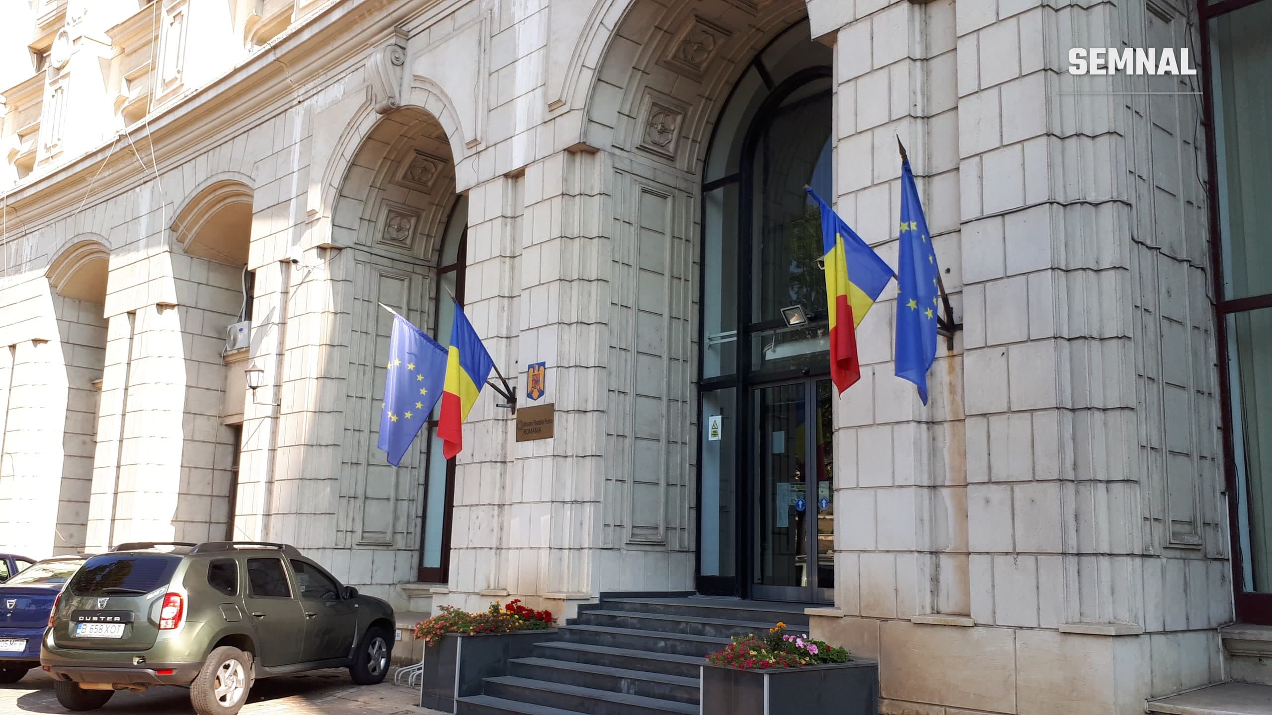 Intrarea în sediul Ministerului Finanțelor din București, cu drapelele României și Uniunii Europene lângă ușă