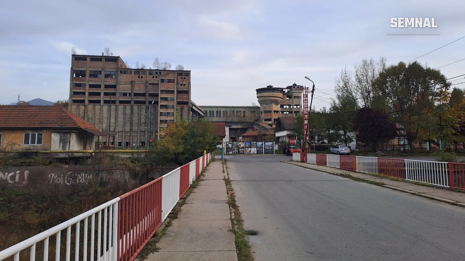 Clădiri industriale din cărămidă ale fostei mine Petrila, cu turnuri de apă în fundal, văzute de pe un pod rutier din orașul Petrila, județul Hunedoara