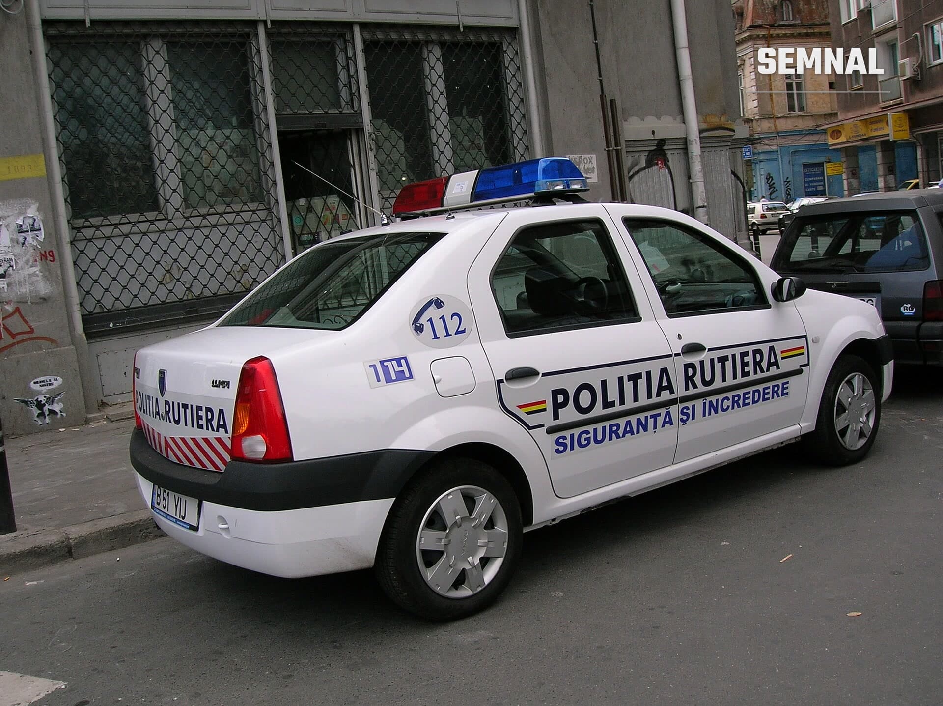 Autospecială de poliție albă, cu girofar albastru, parcată pe o stradă din București