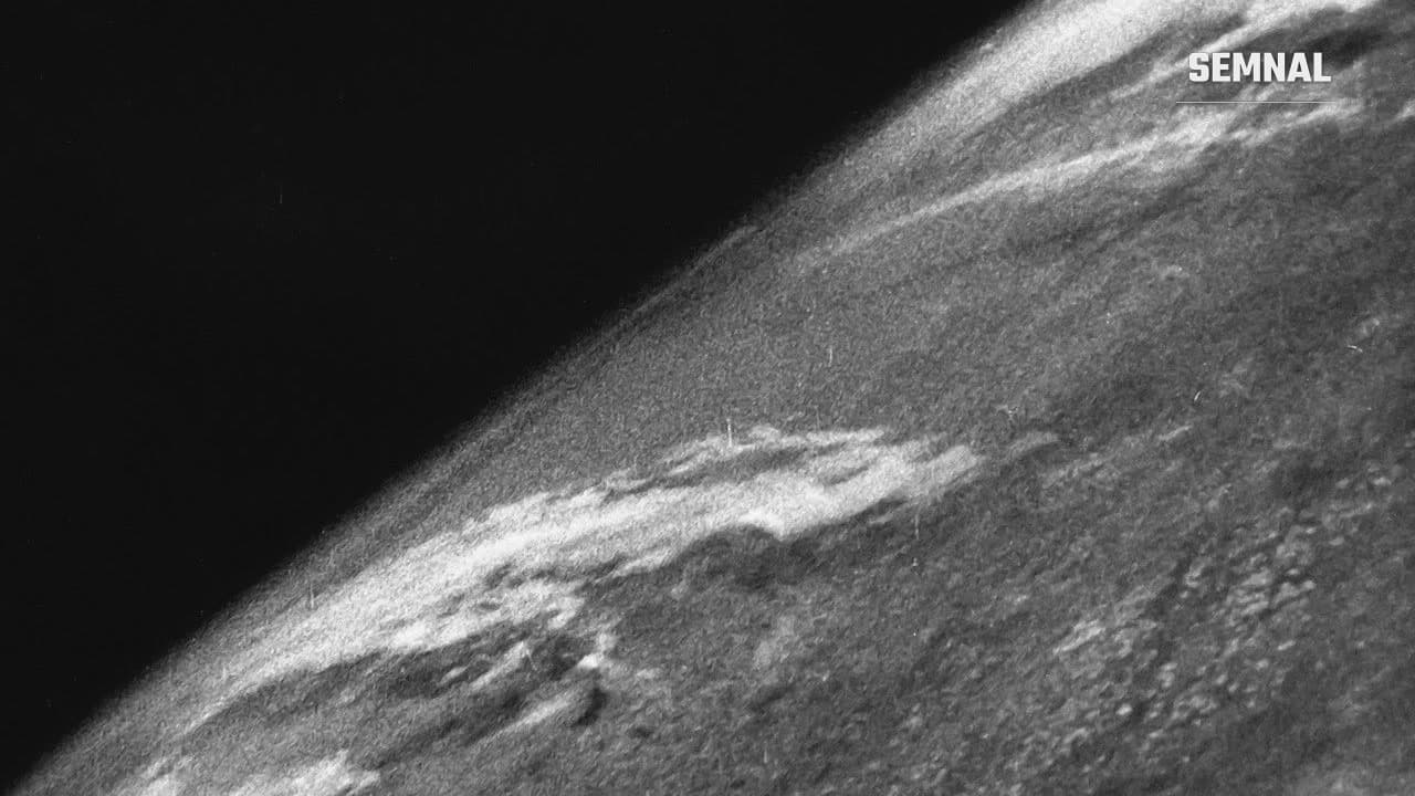 Fotografie alb-negru, granulată, a Pământului văzut de la 105 km, făcută de pe racheta V-2 nr. 13 pe 24 octombrie 1946, cu nori și cer negru