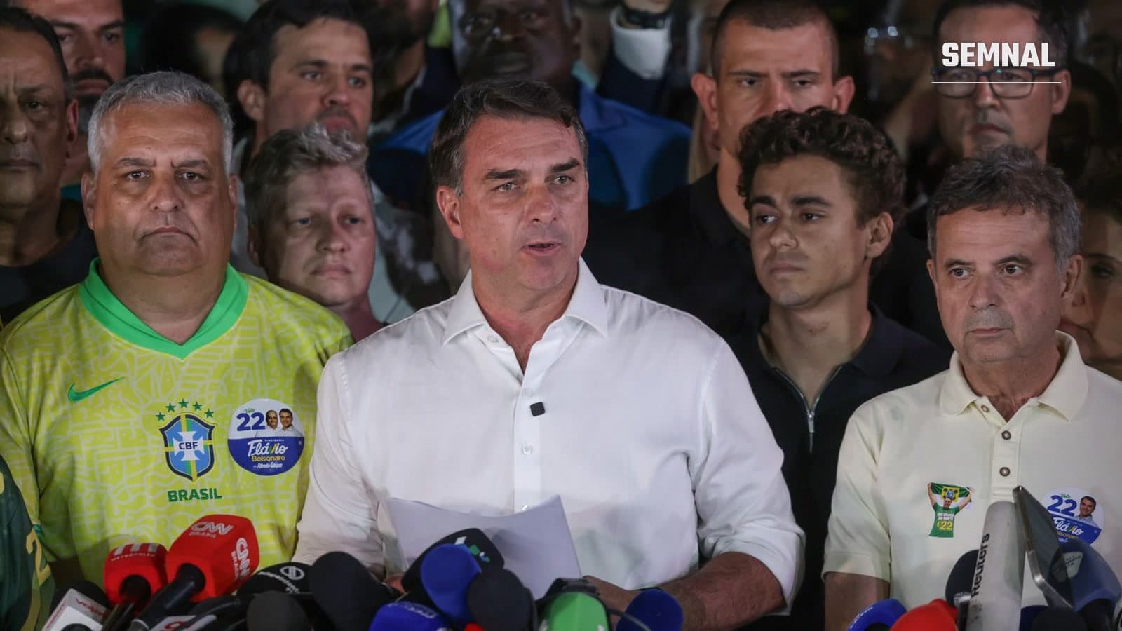 Senatorul Flávio Bolsonaro, în cămașă albă, vorbește jurnaliștilor la Brasília, înconjurat de susținători, după înfrângerea din turul doi.