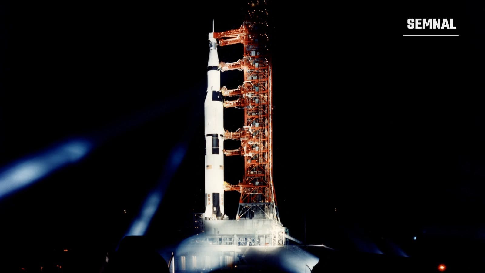 Racheta Saturn V a misiunii Apollo 11, luminată de reflectoare pe rampa de lansare, noaptea, în 1969