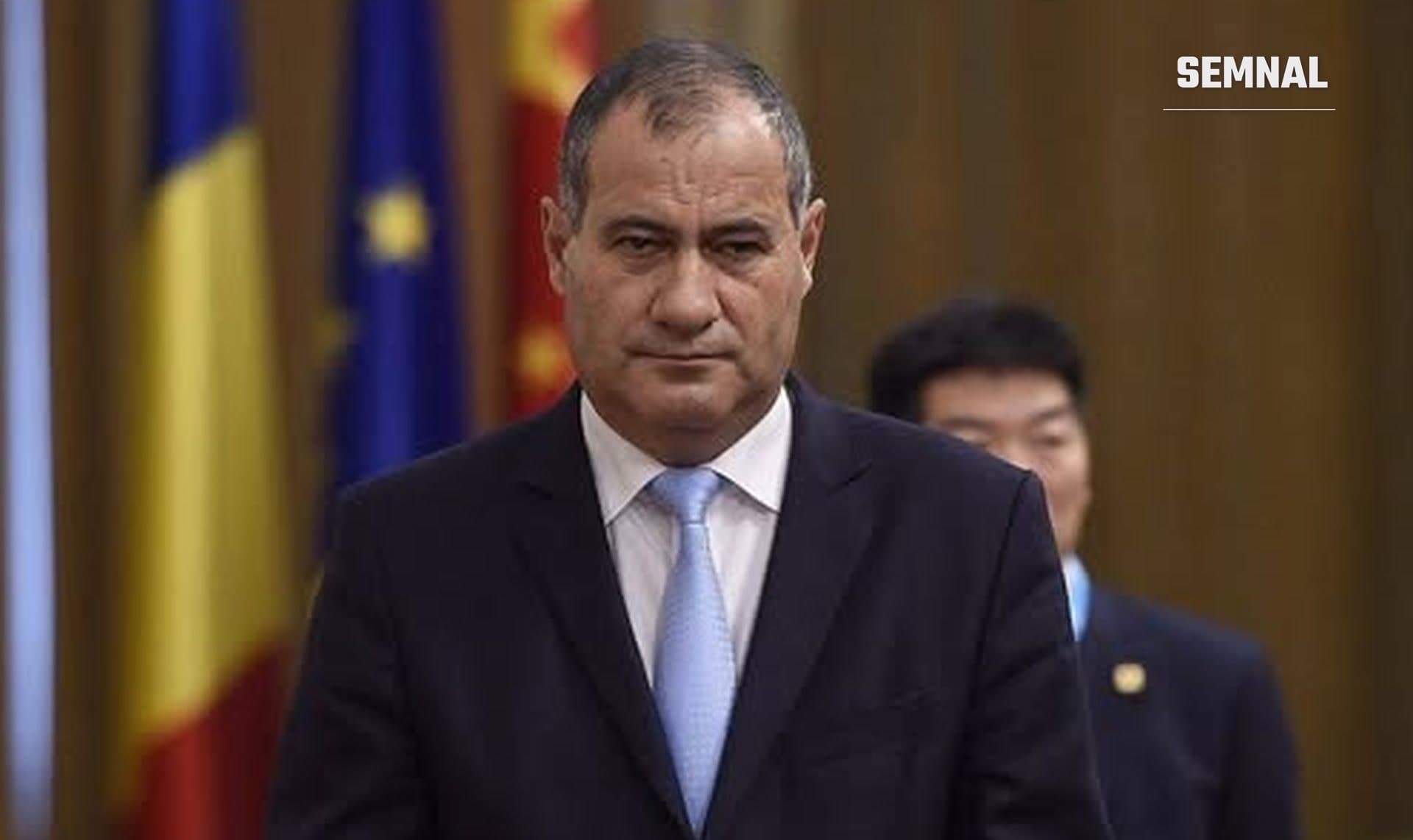 Vicepremierul Marian Neacșu, în costum închis și cravată albastră, în fața drapelelor României și Uniunii Europene