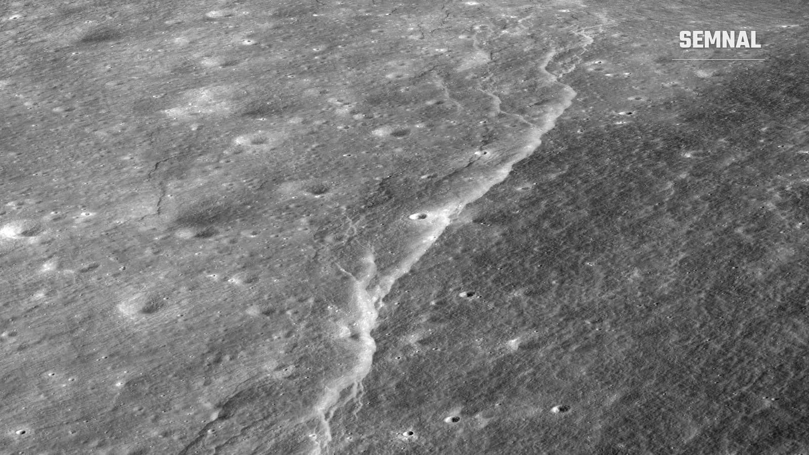 Vedere oblică în alb-negru a unei falii lunare (scarpă lobată) lângă craterul Slipher: o creastă luminoasă, în formă de treaptă, traversează o câmpie presărată cu cratere mici.