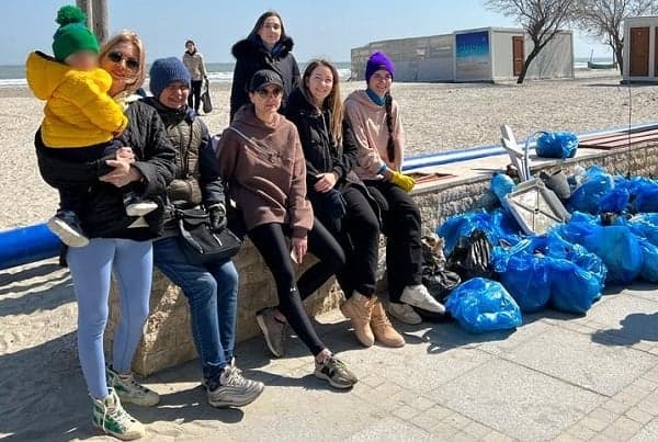 Refugiații ne curăță plaja de gunoaie