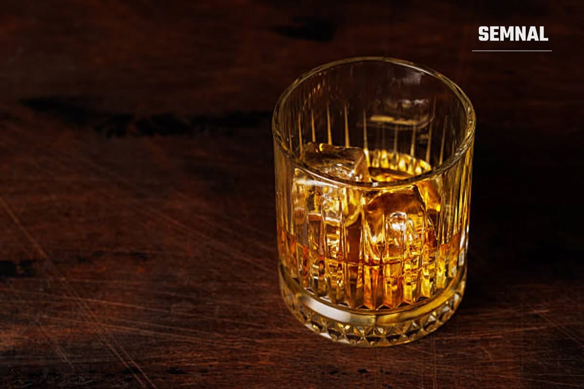 În imagine se află un pahar de whiskey