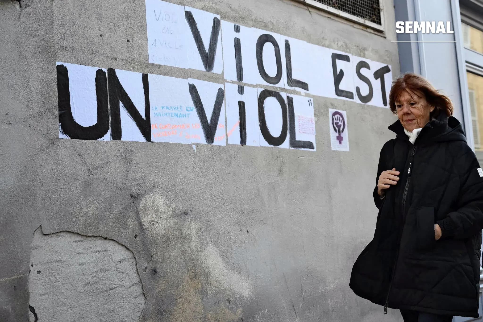 Gisèle Pelicot trecand pe langa un zid pe care scrie ca un viol, e un viol