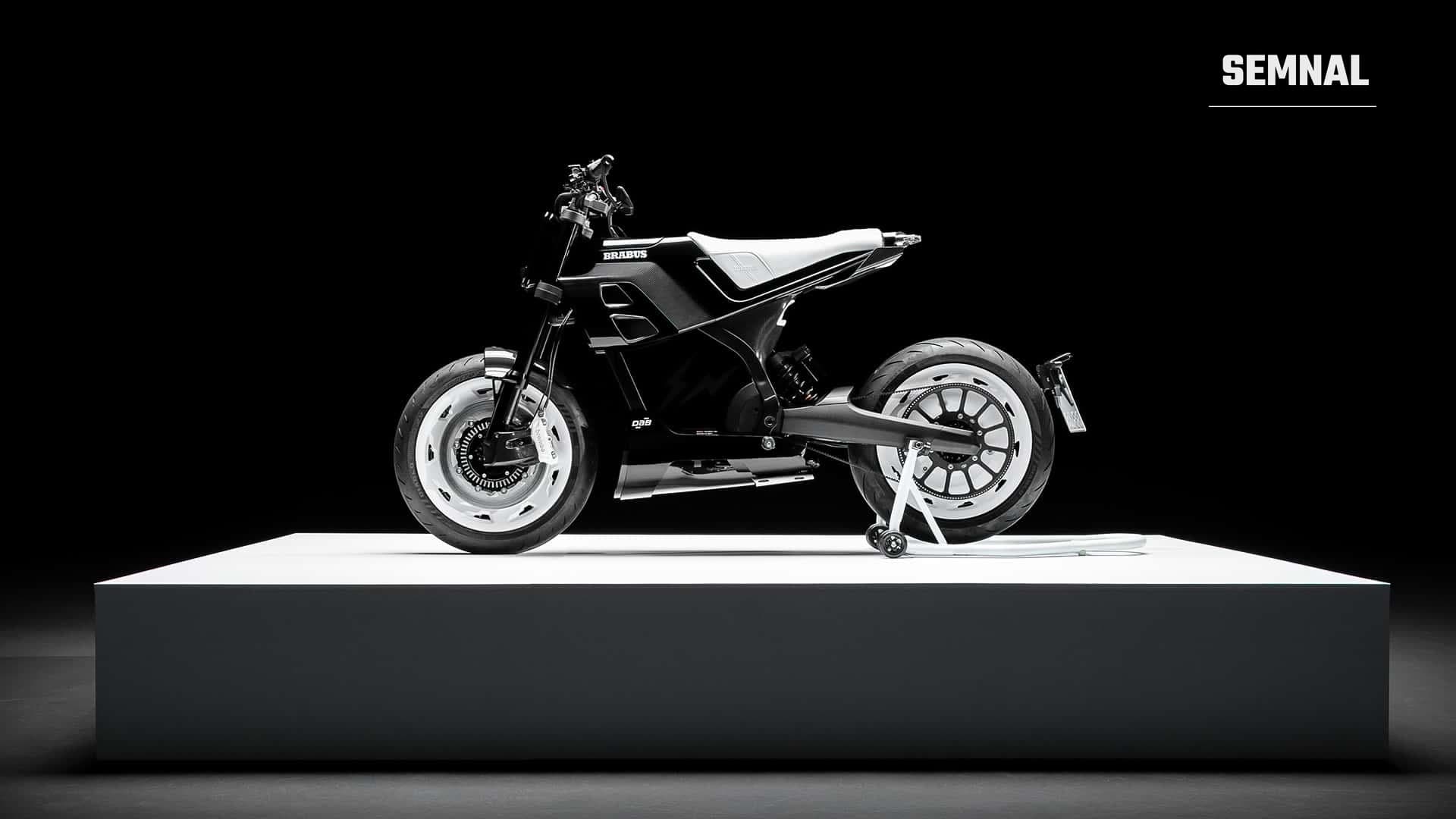 Motocicleta electrică DAB 1α, în alb și negru, văzută din lateral, cu șa neagră, roți cu spițe și amortizor auriu, pe un podium negru