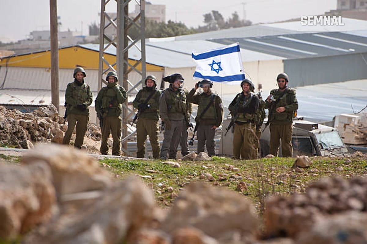Mai mulți soldați ai armatei israeliene, cu steagul Israelului în fundal.